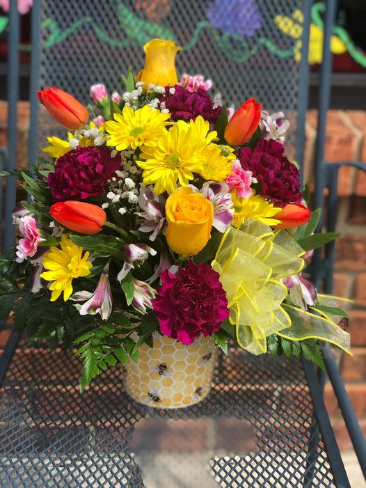 Bright mixed bouquet in a honeycomb-patterned vase with yellow ribbon