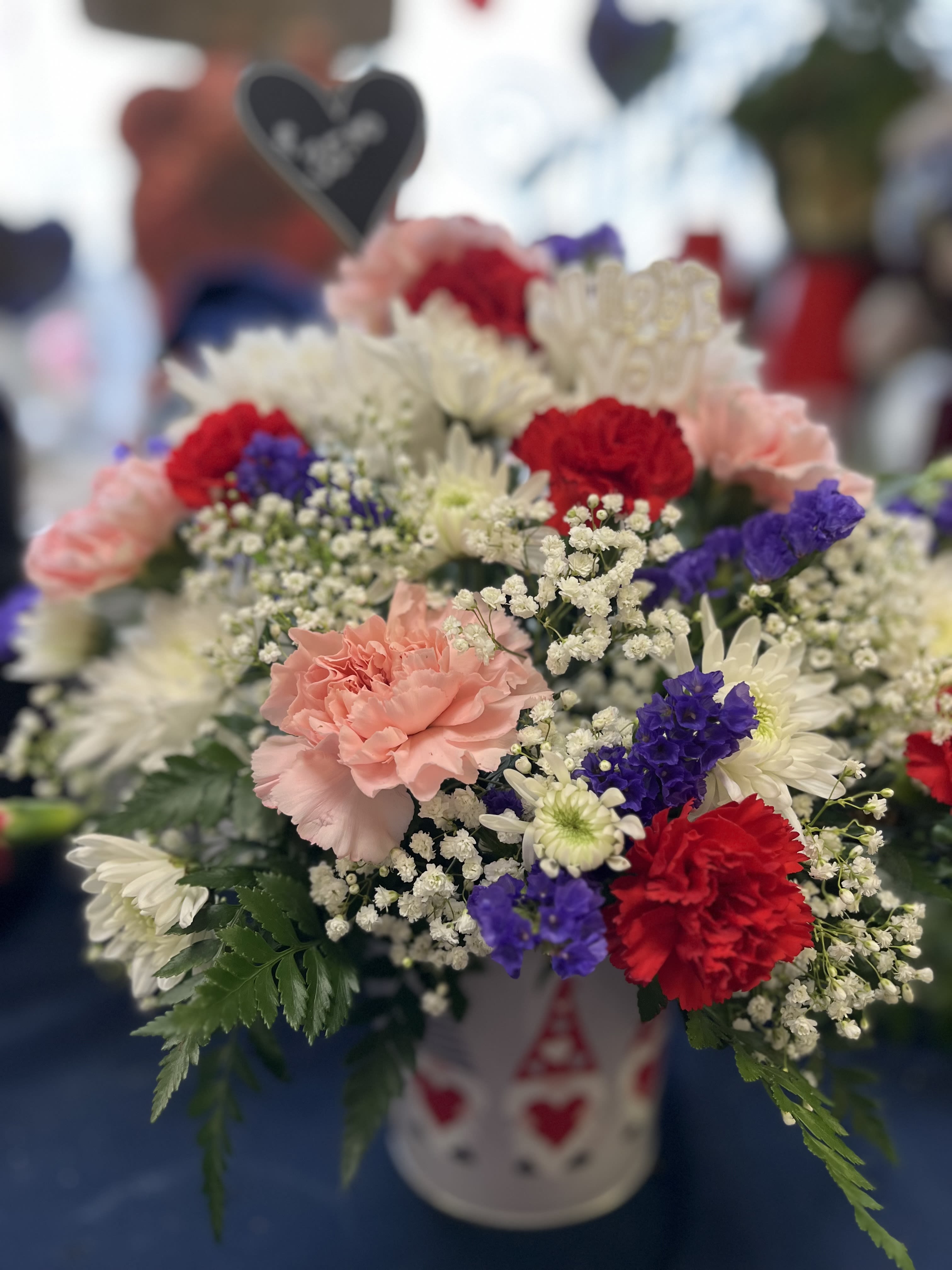 Mixed bouquet of carnations, daisies, and baby's breath in a white container