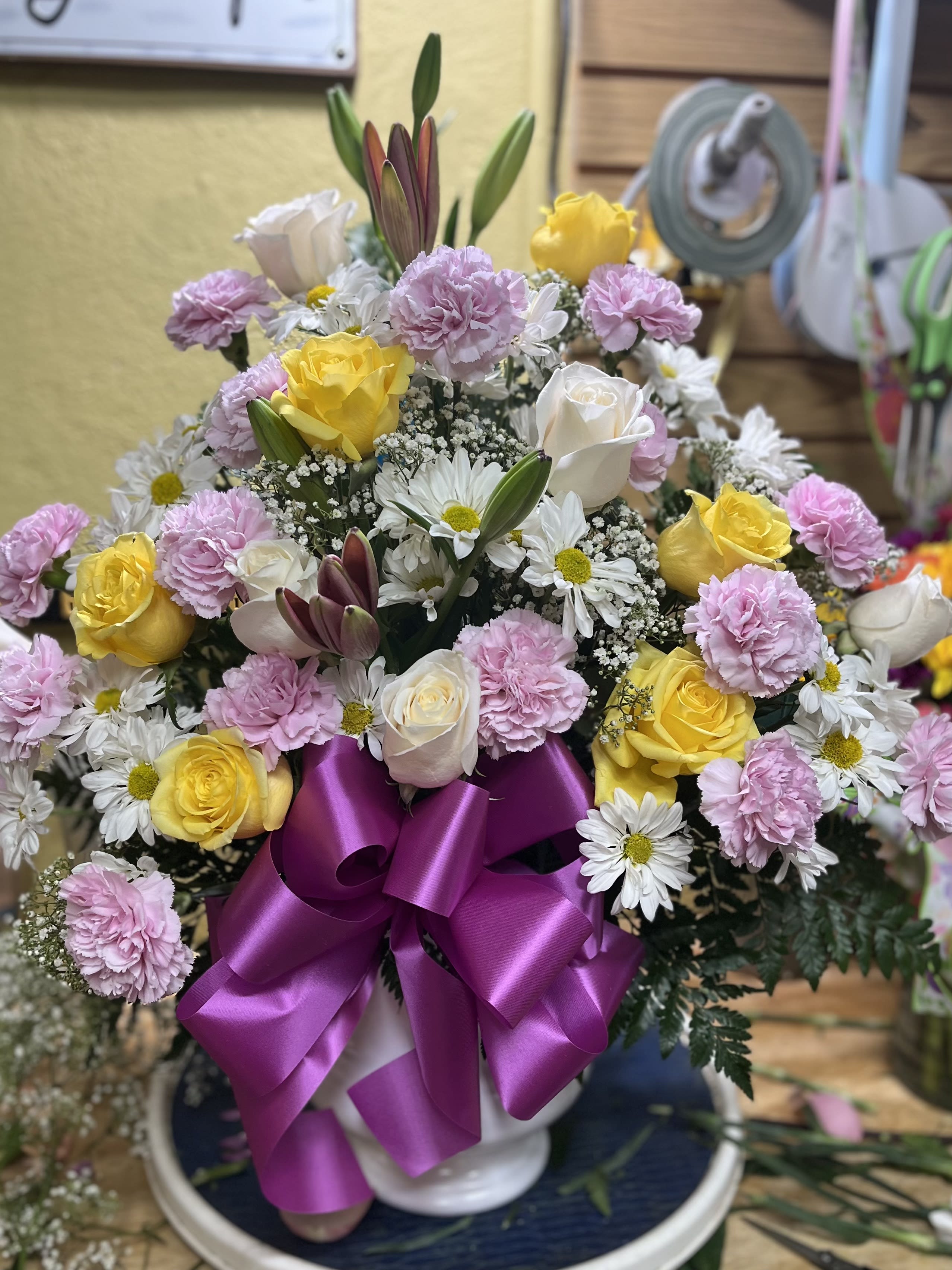 Bouquet of yellow and white roses with pink carnations and daisies in a vase