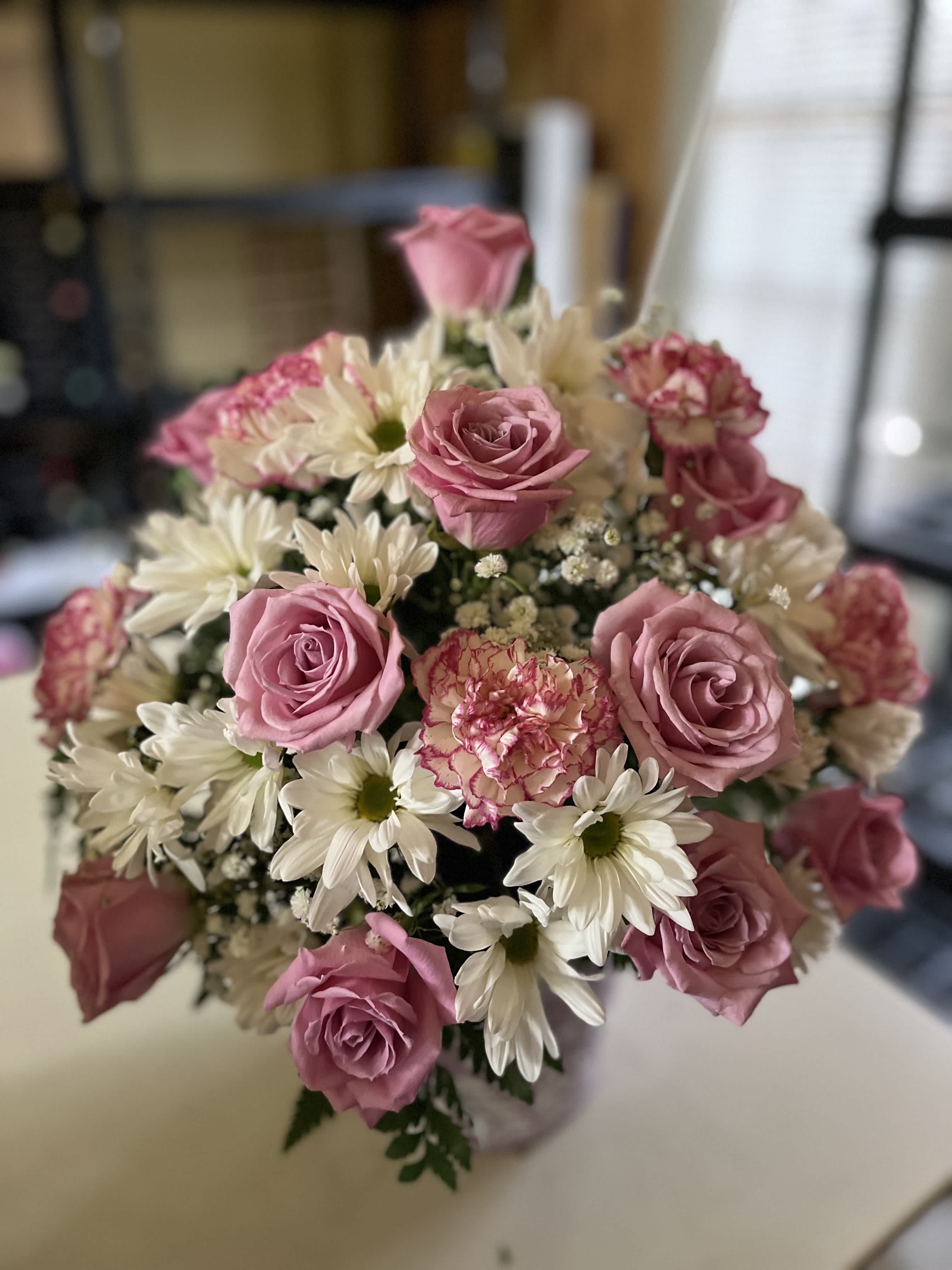 Bouquet of pink roses and white daisies with a pink carnation