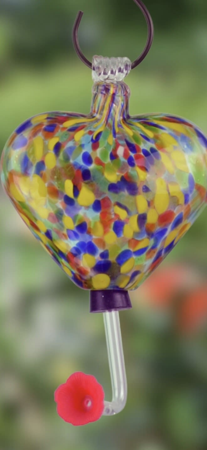Heart Hummingbird Feeder - Attract the hummingbirds with this multi-color glass heart single-feed hummingbird feeder. This glass hummingbird feeder has a 6 oz capacity and vibrant blown glass finish. Made from durable, weather-resistant materials, it's designed to attract hummingbirds while adding a colorful touch to any garden or outdoor space. Easy to fill, clean, and hang, making it a thoughtful gift for nature lovers and garden enthusiasts.  ??????? ???????: • 6-ounce nectar capacity • 1 feeding port • S-hook included • Easy to clean • Crafted from glass, metal, and plastic • Weather-resistant for year-round use • Ideal for patios, porches, and gardens • Height: 13" • Width: 4.35" Outdoor Decor | Weatherproof Yard Art | Whimsical Gifts | Garden Ornaments | Gifts for Gardeners | Seasonal Décor | Nature-Inspired Art