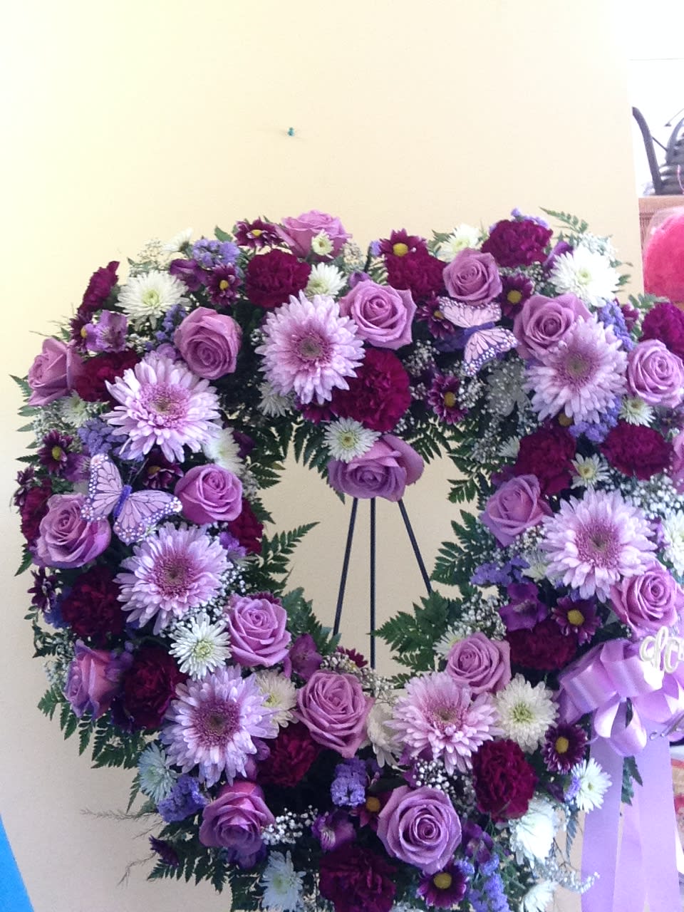 Purple floral wreath on an easel with roses and daisies