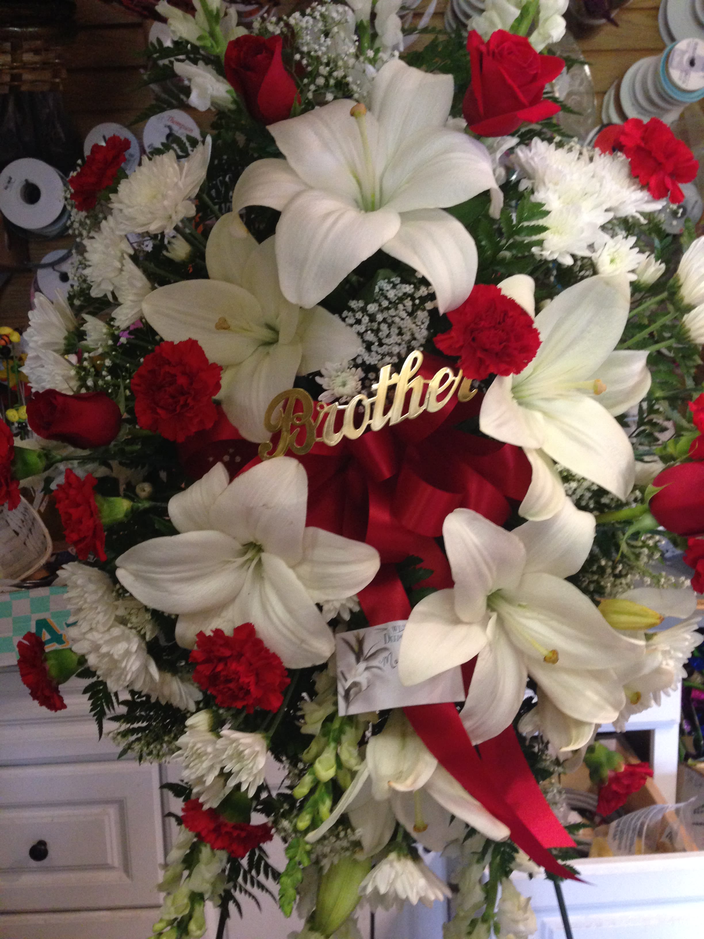 Large red and white funeral wreath with lilies, roses, and carnations
