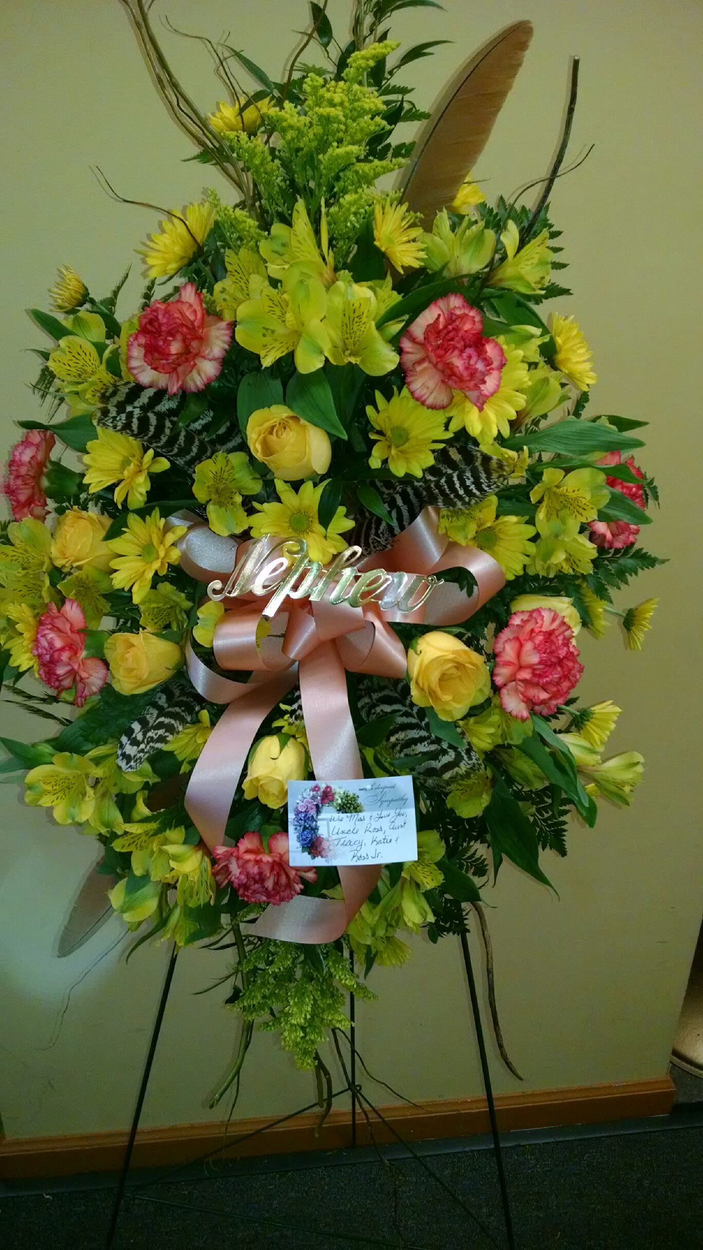 Standing floral spray with yellow and pink flowers on an easel