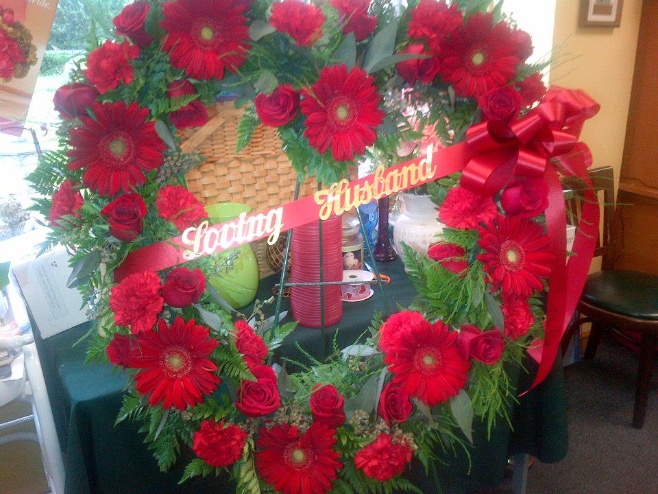 Red rose and gerbera daisy wreath with a ribbon banner