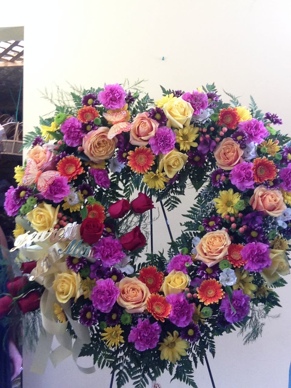 Large circular floral wreath with roses, carnations, and daisies