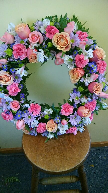 Circular floral wreath with pink roses and purple daisies
