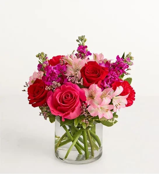 Bouquet of red and pink roses with pale pink alstroemeria in a glass vase