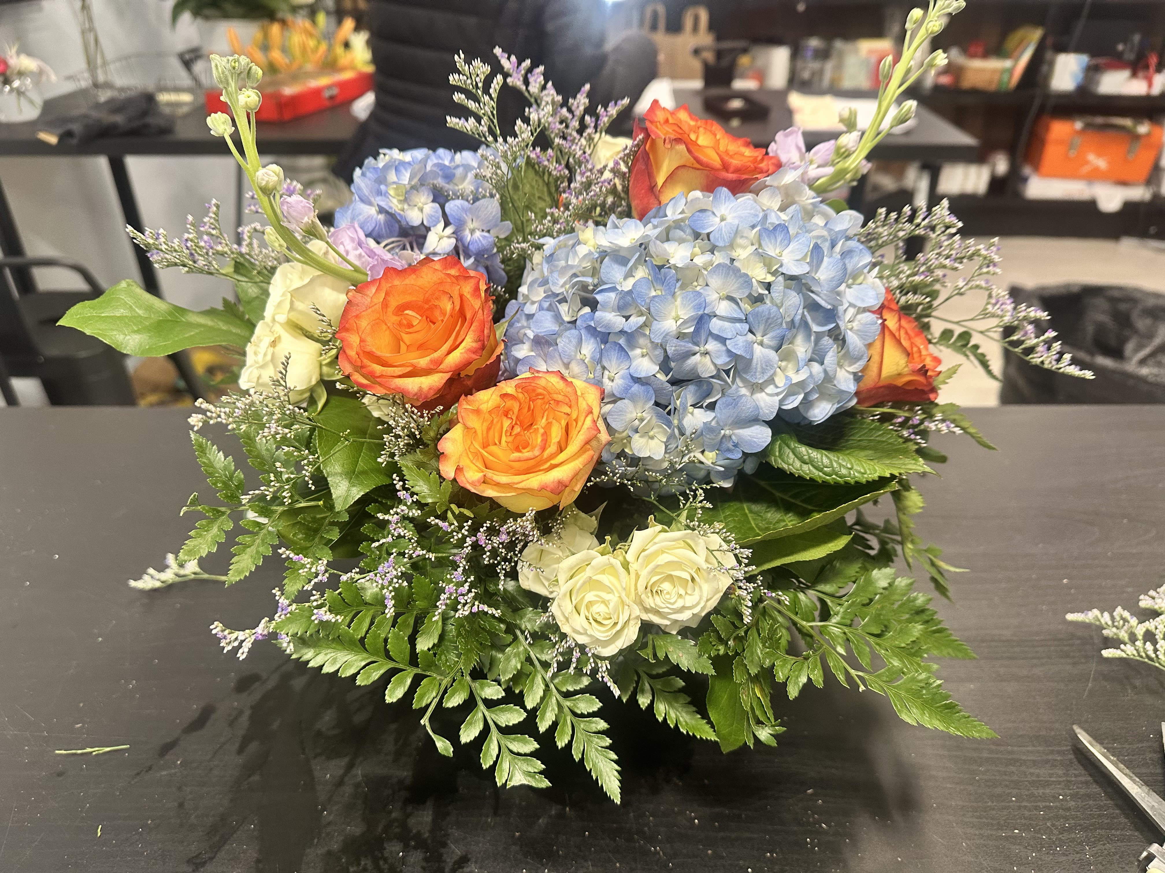 Bouquet of blue hydrangeas and orange roses with white roses