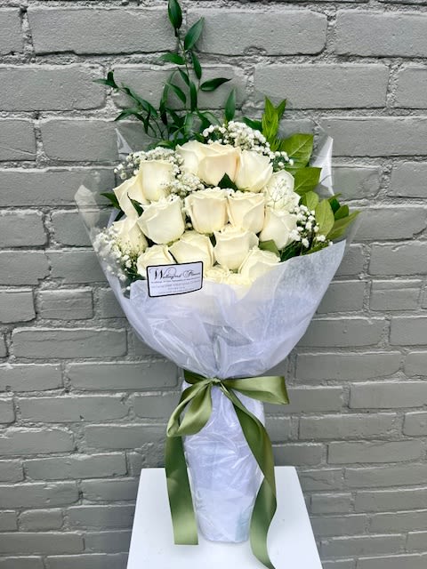 Pure Love Wrapped White Roses - Playa Blanca white roses with elegant greens tied together with a ribbon. Photo shows 18 roses and would reflect the Deluxe size pricing. Standard size is 12 roses and Premium size is 24 roses.