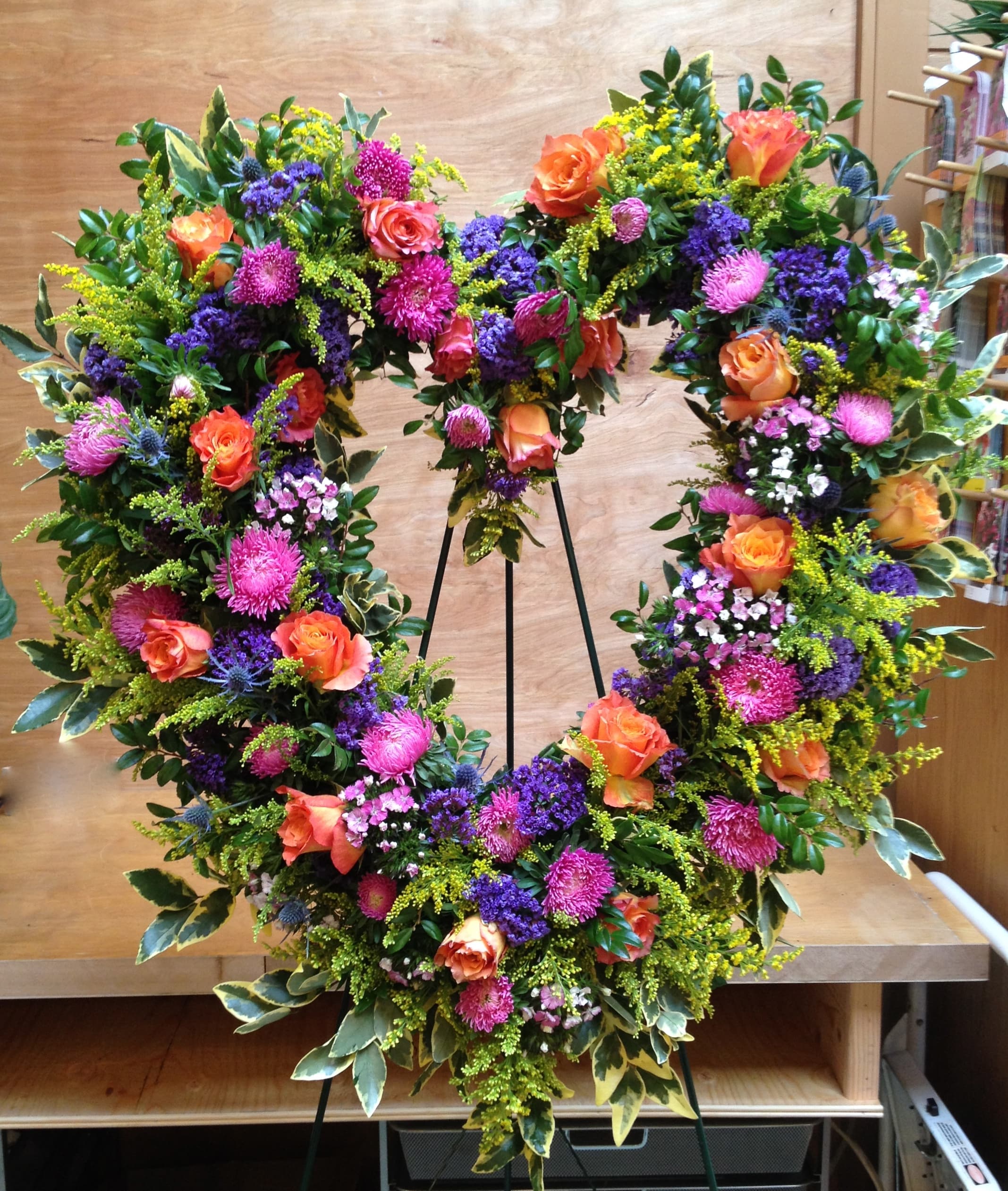 Large floral wreath with orange roses, pink blooms, and purple accents