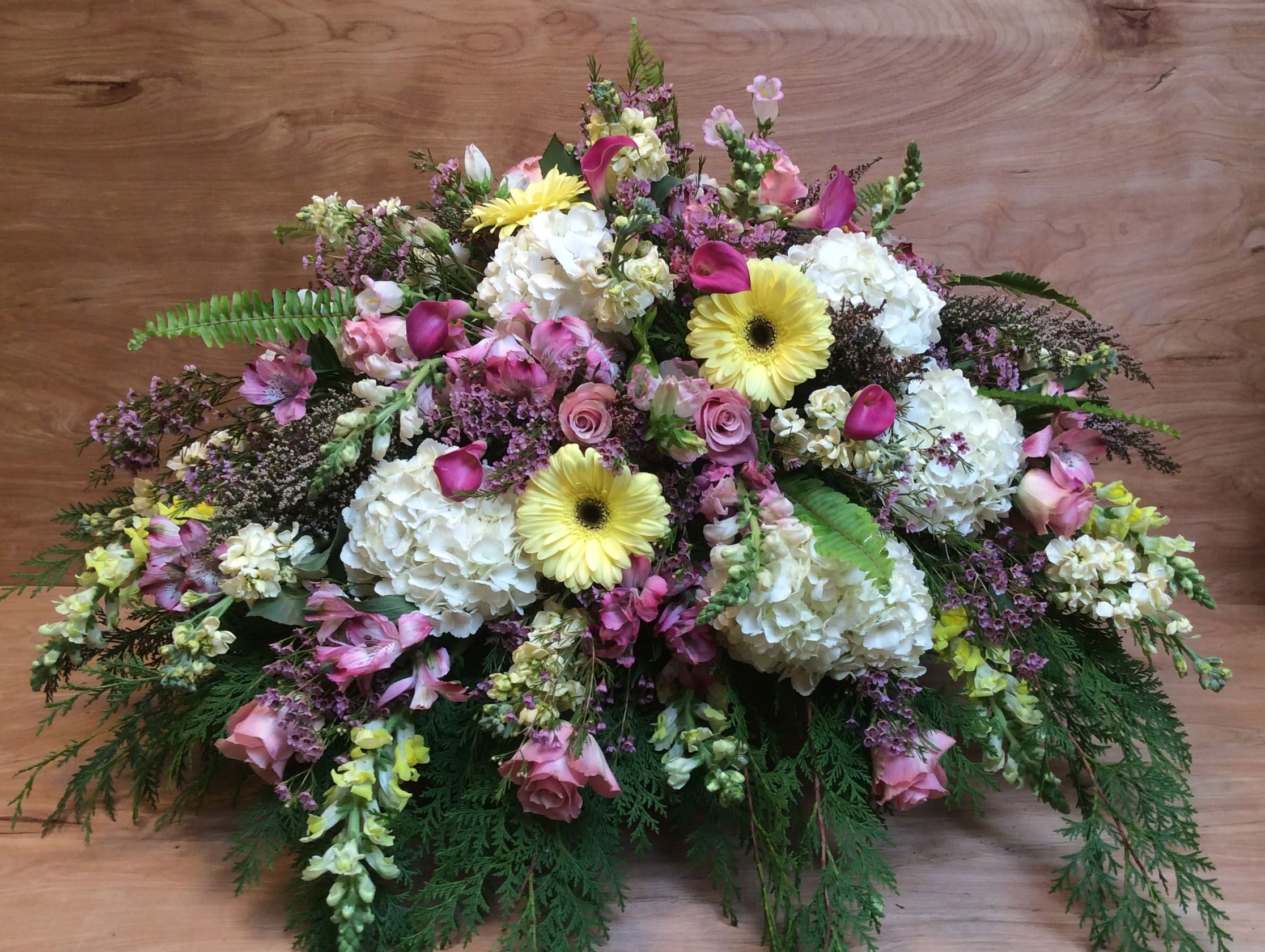 Large mixed floral arrangement with white hydrangeas, pink roses, and yellow gerbera daisies