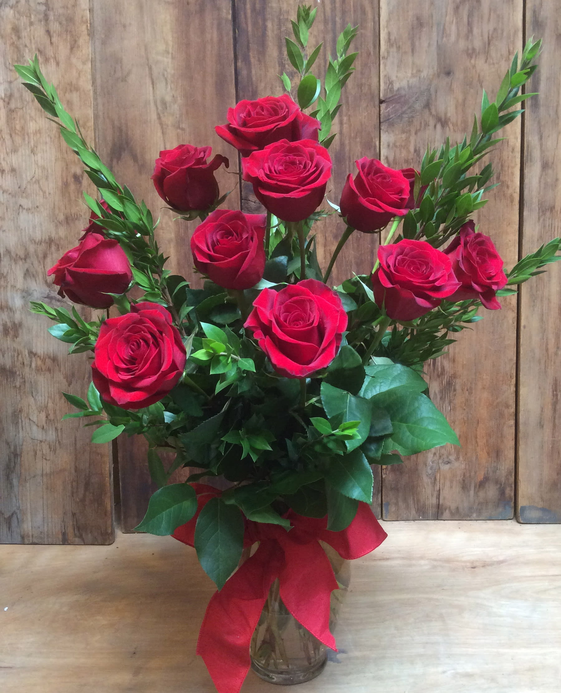 Bouquet of red roses in a clear glass vase with a red ribbon