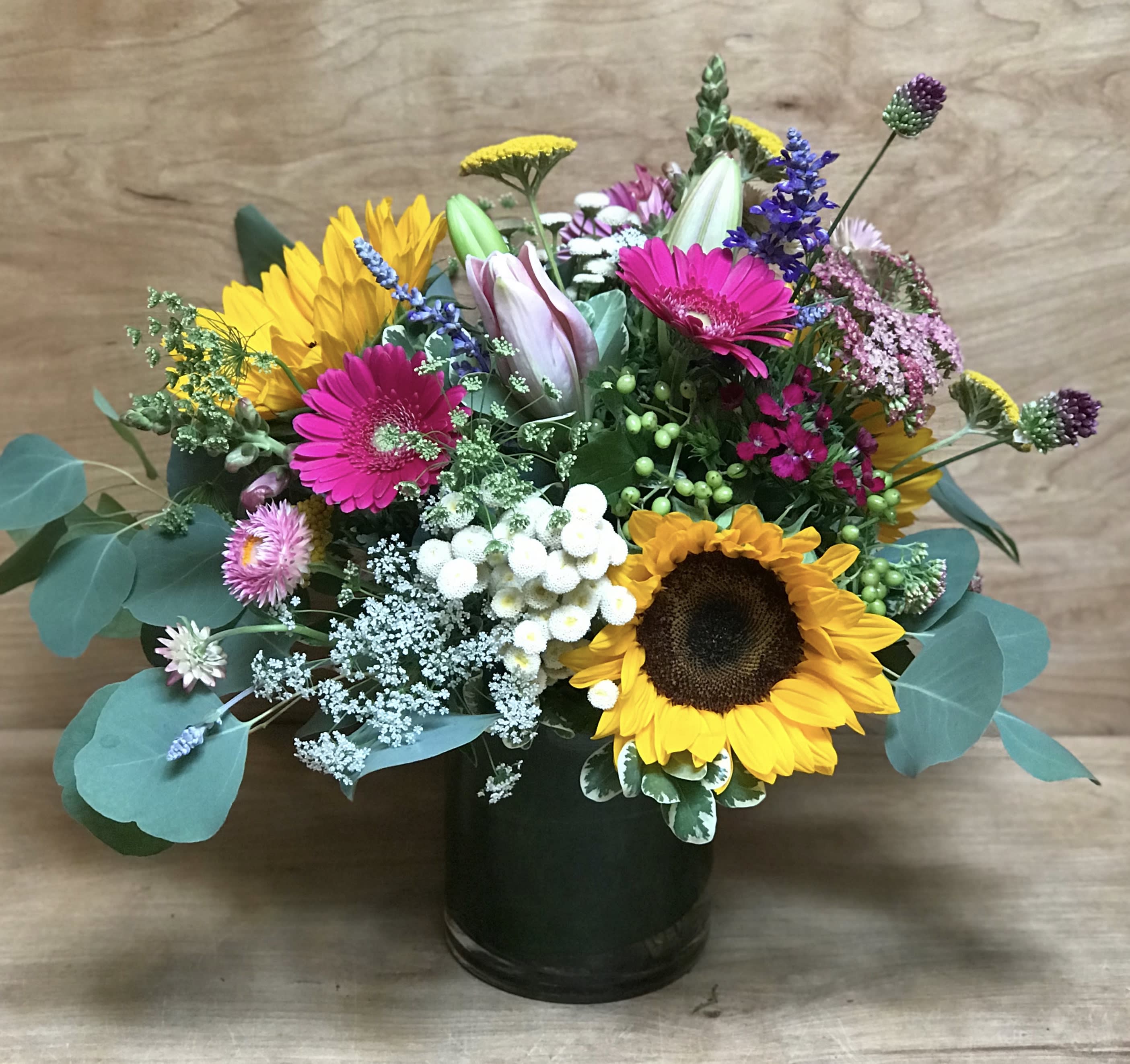 Mixed bouquet with sunflowers, pink gerberas, and a dark vase