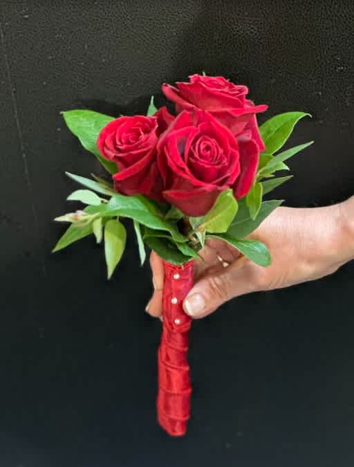 Small bouquet of red roses with green leaves and a red wrapped handle
