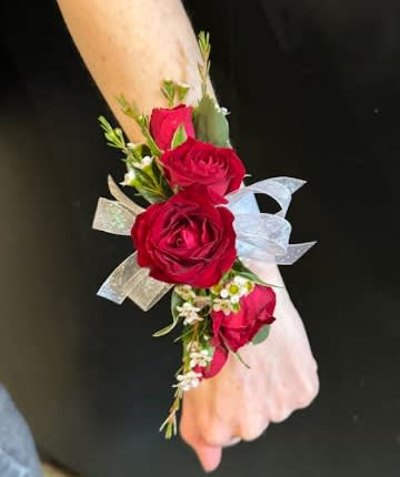 Red rose wrist corsage with ribbon on a wrist