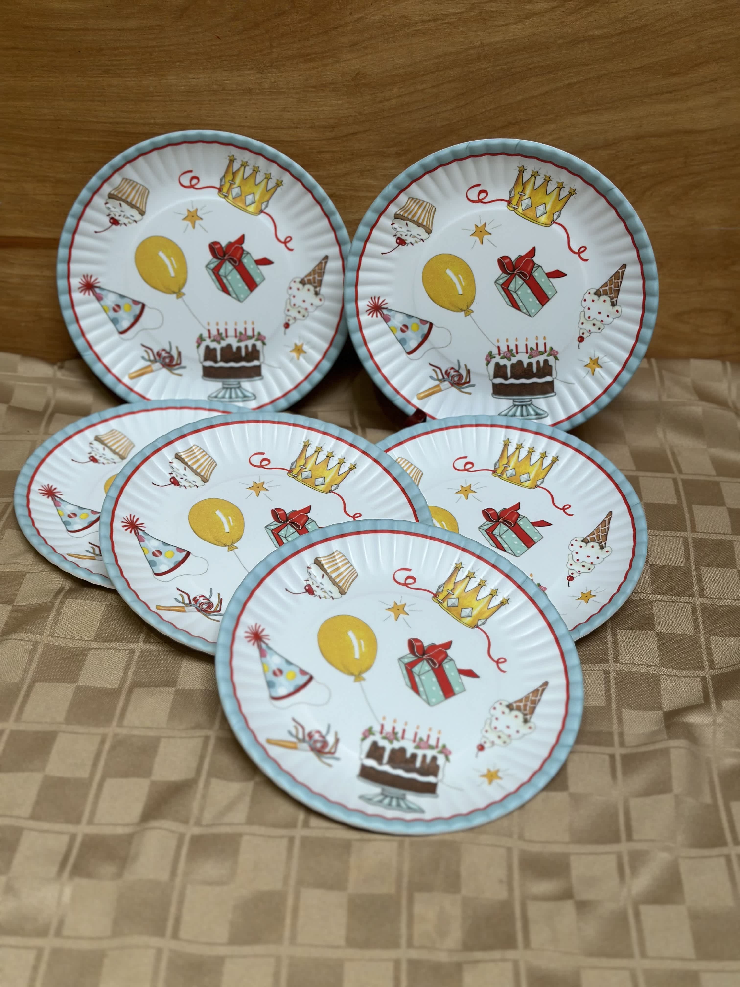 Five birthday-themed paper plates with cakes, balloons, and party hats