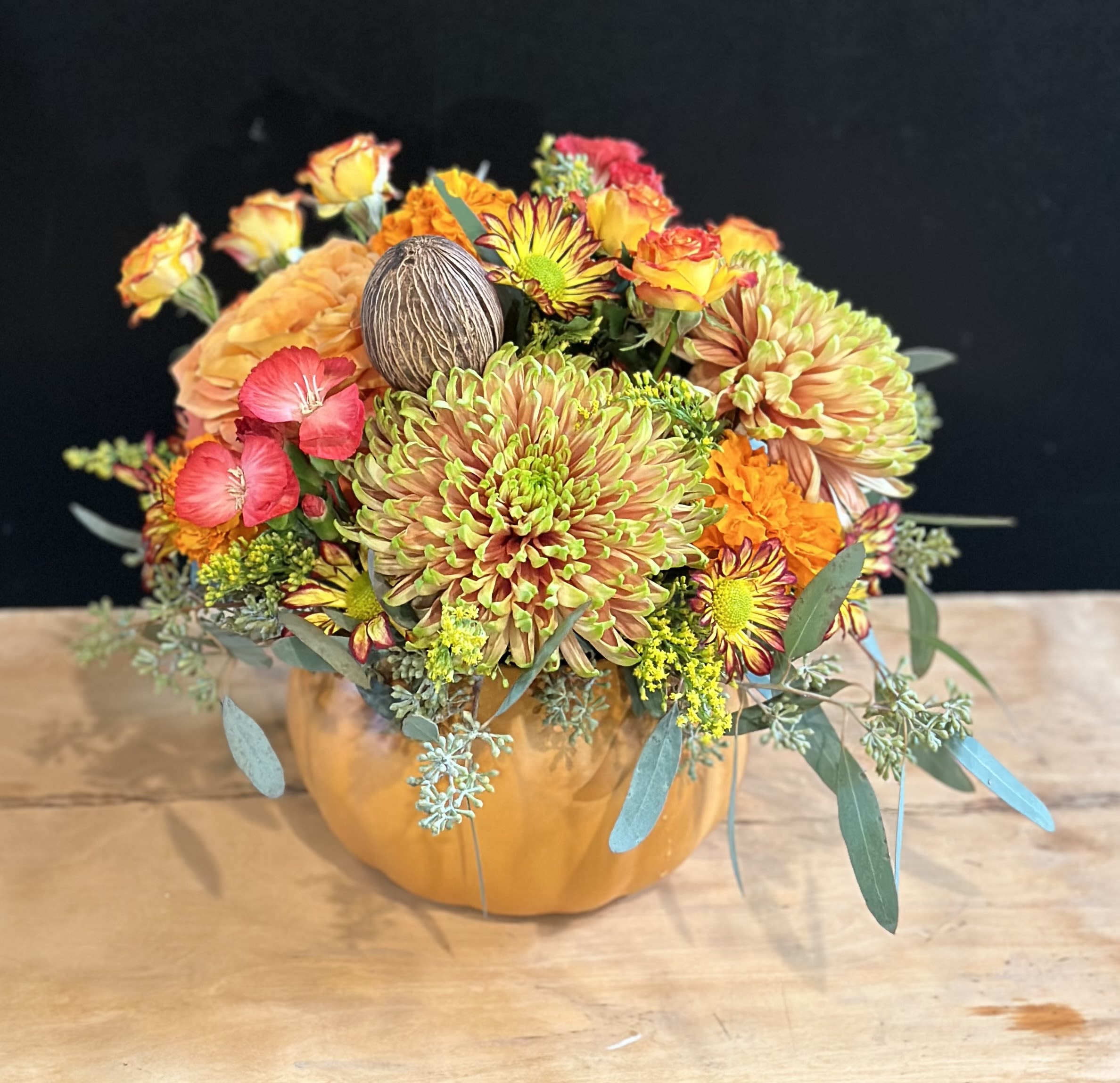 Mixed orange and pink flowers arranged in a pumpkin-shaped container