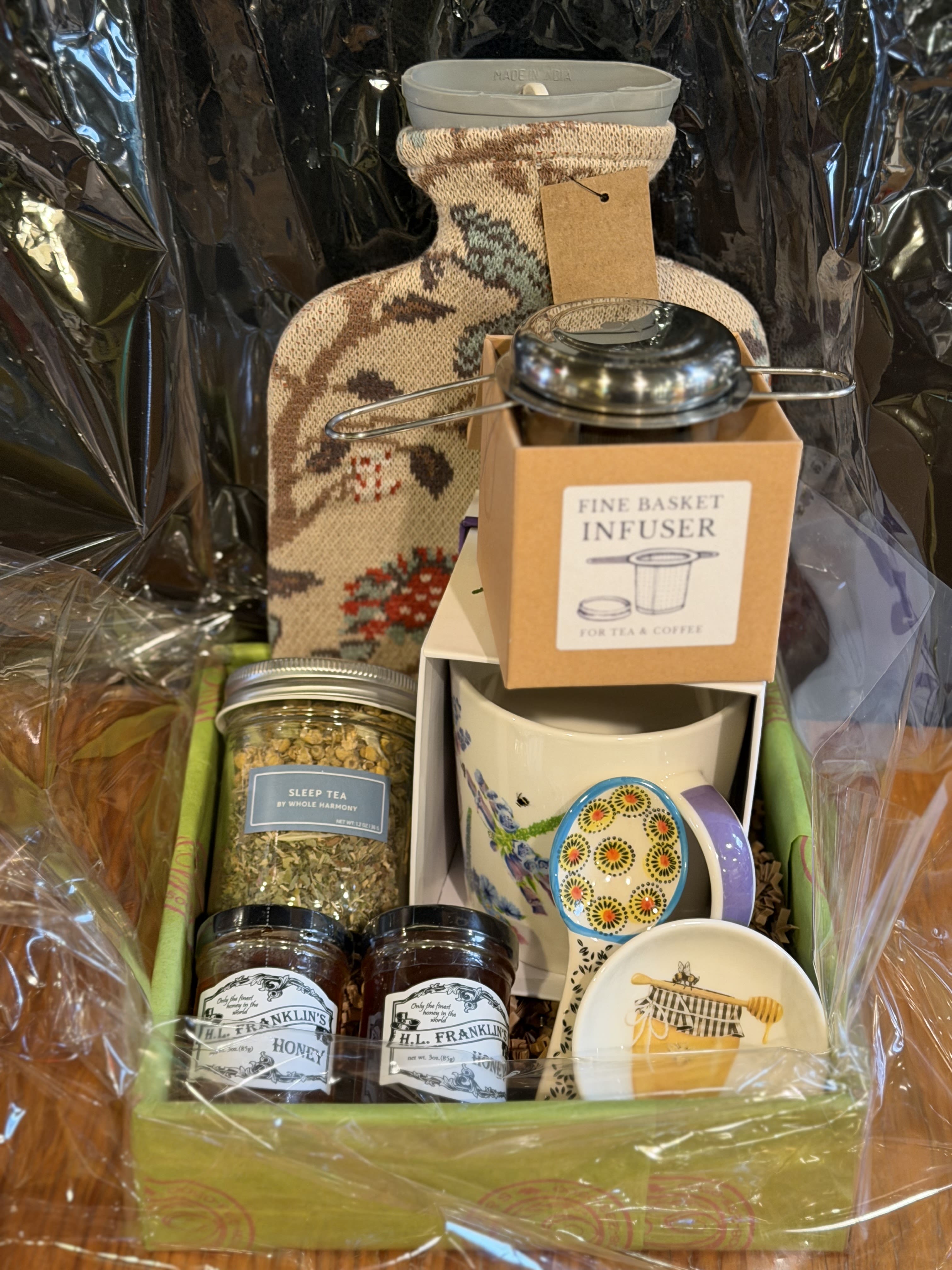 Gift basket with tea, honey, mugs, and a decorative bottle-shaped container