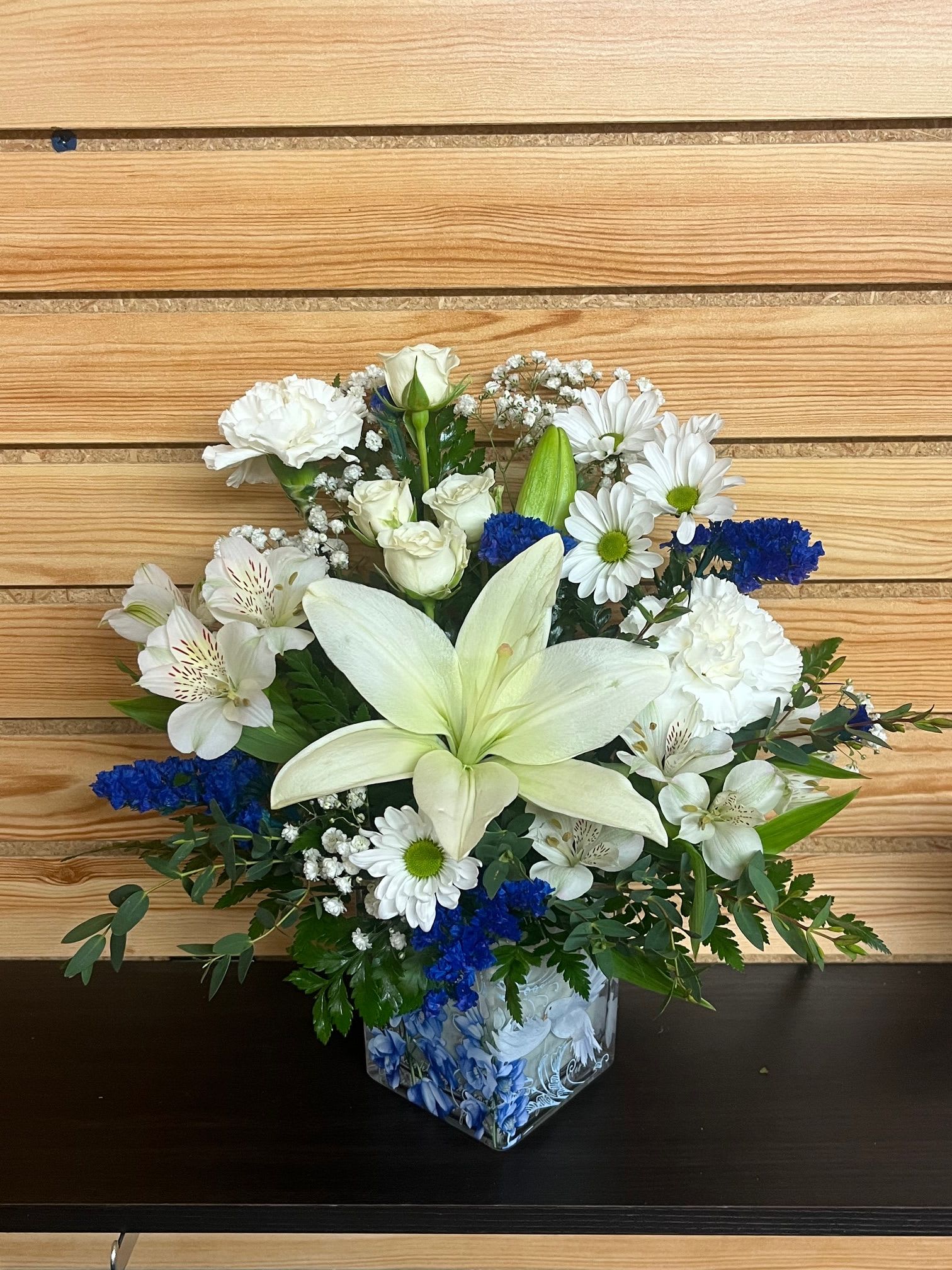 Peaceful White Dove - This cube with blue florals and a peaceful Dove offers grace and serenity with its white lilies, daisies, alstroemeria, carnations, and blue statice.