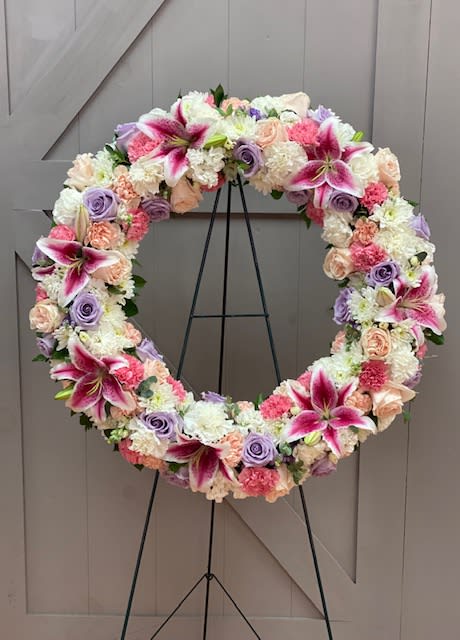 Sweet Sympathy - This beautiful floral wreath is filled with lilies, roses, carnations and stock in the most beautiful colors.  