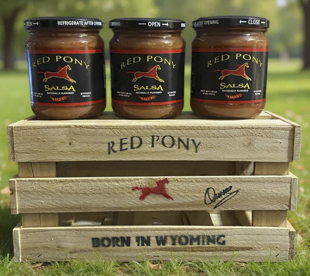 Three jars of Red Pony salsa in a wooden crate outdoors