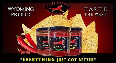 Three jars of salsa with tortilla chips and red peppers on a red background