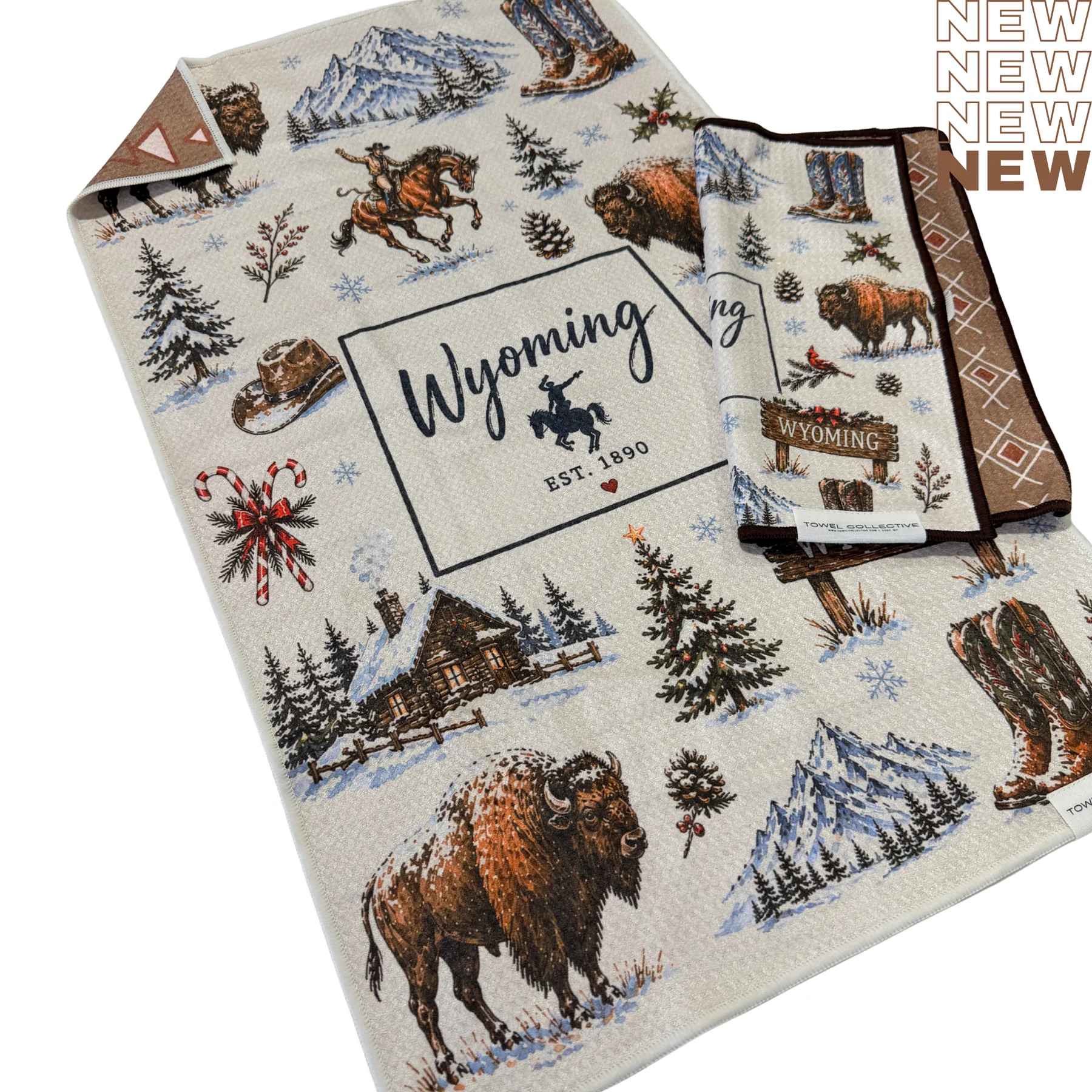 Folded Wyoming-themed towel with bison, boots, and snowy cabin illustrations