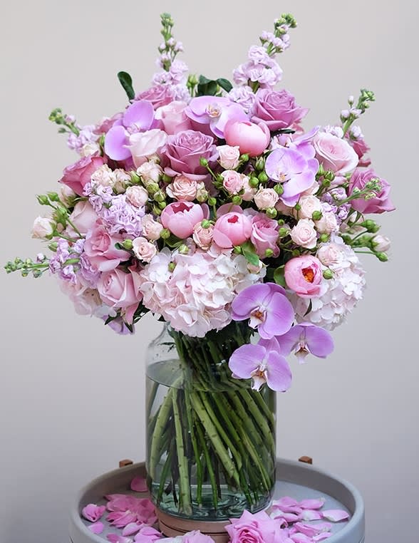 exquisite flower bouquet  - This exquisite flower bouquet in rich shades of pink showcases a captivating ensemble of roses, hydrangeas, peonies, and orchids, thoughtfully selected to create a harmonious blend of colours and textures. Presented in a minimal clear glass vase that adds a touch of modern simplicity, accentuating the grandeur of the floral arrangement. Whether adorning your home, office, or special event, this luxurious bouquet promises to leave a lasting impression.