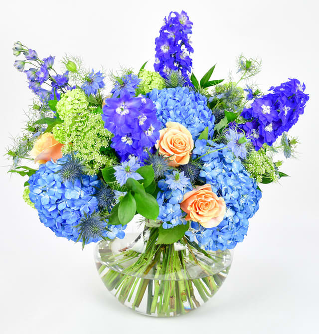 Blue and peach flower arrangement in a clear glass vase