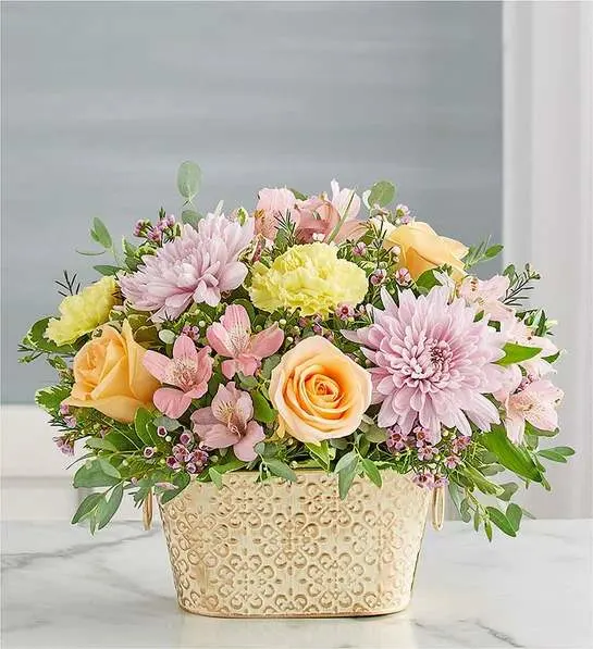 Loving Remembrance  Multicolor Pastel - Celebrate the life of a loved one with our beautiful floral tribute. A mix of blooms in soothing pastel shades is a symbol of enduring love. Designed in our Remembrance Cachepot, featuring an embossed pattern and finished with a gold brushed ivory surface.