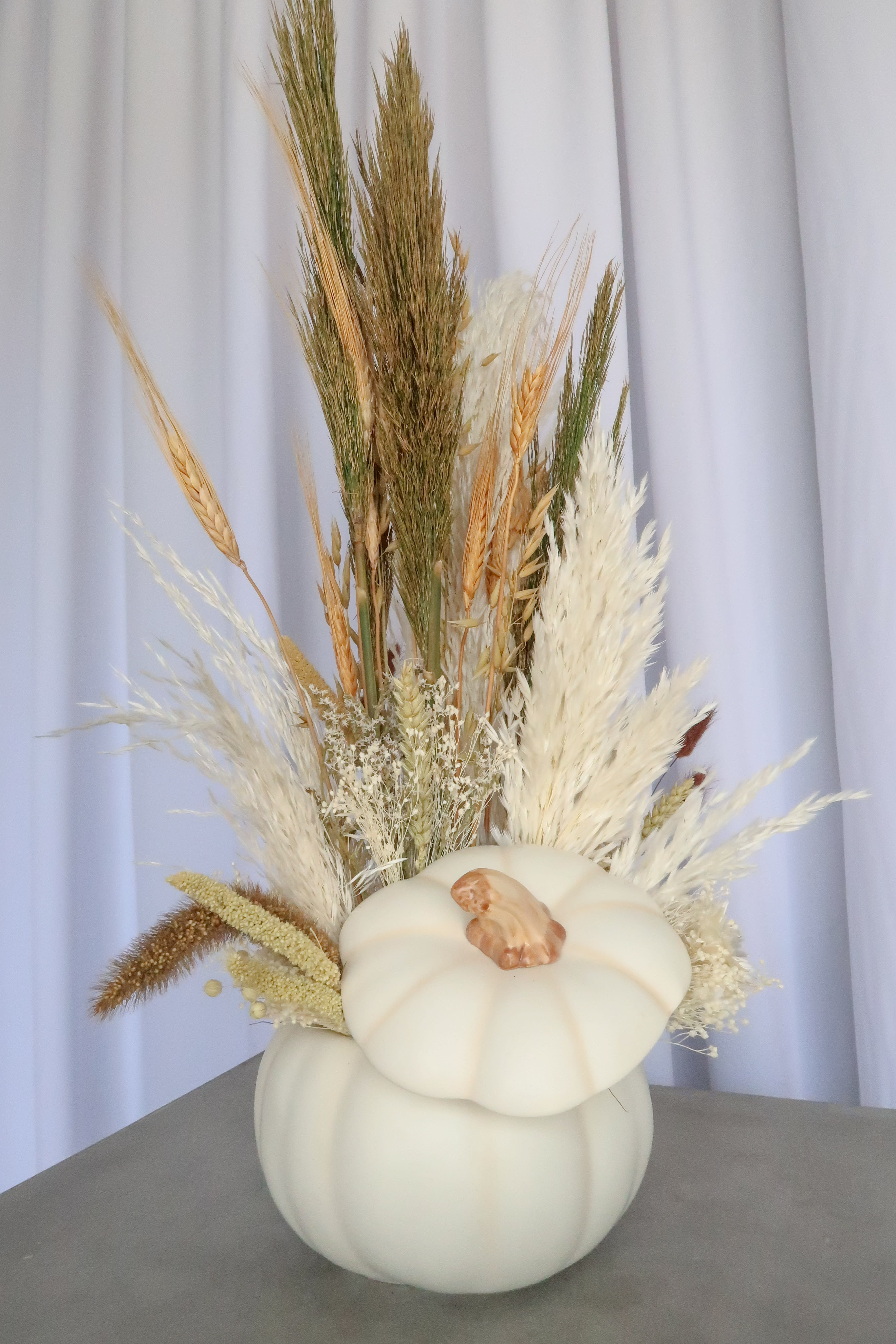 White pumpkin vase filled with dried grasses and wheat