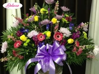Large mixed flower arrangement with a purple ribbon bow