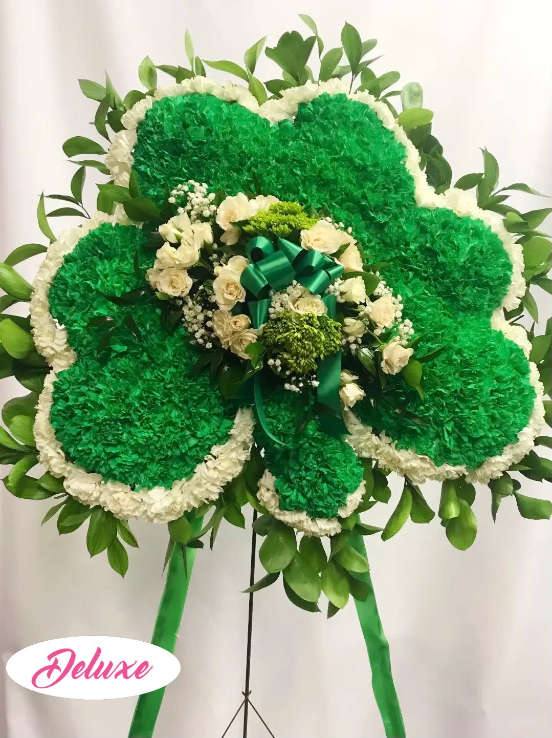 Large green and white floral standing spray with a ribbon bow