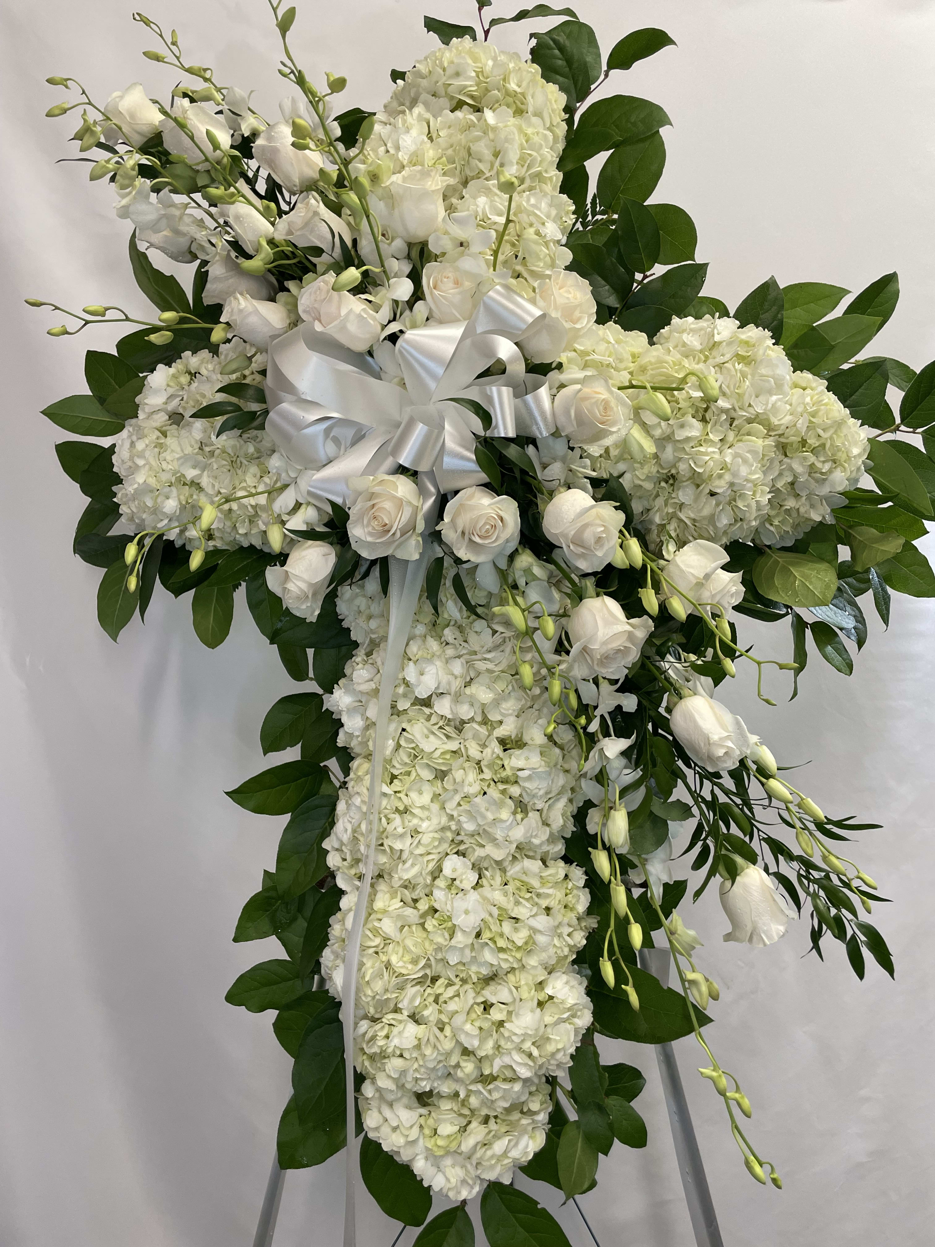 White floral standing spray with roses and hydrangeas on a ribboned easel