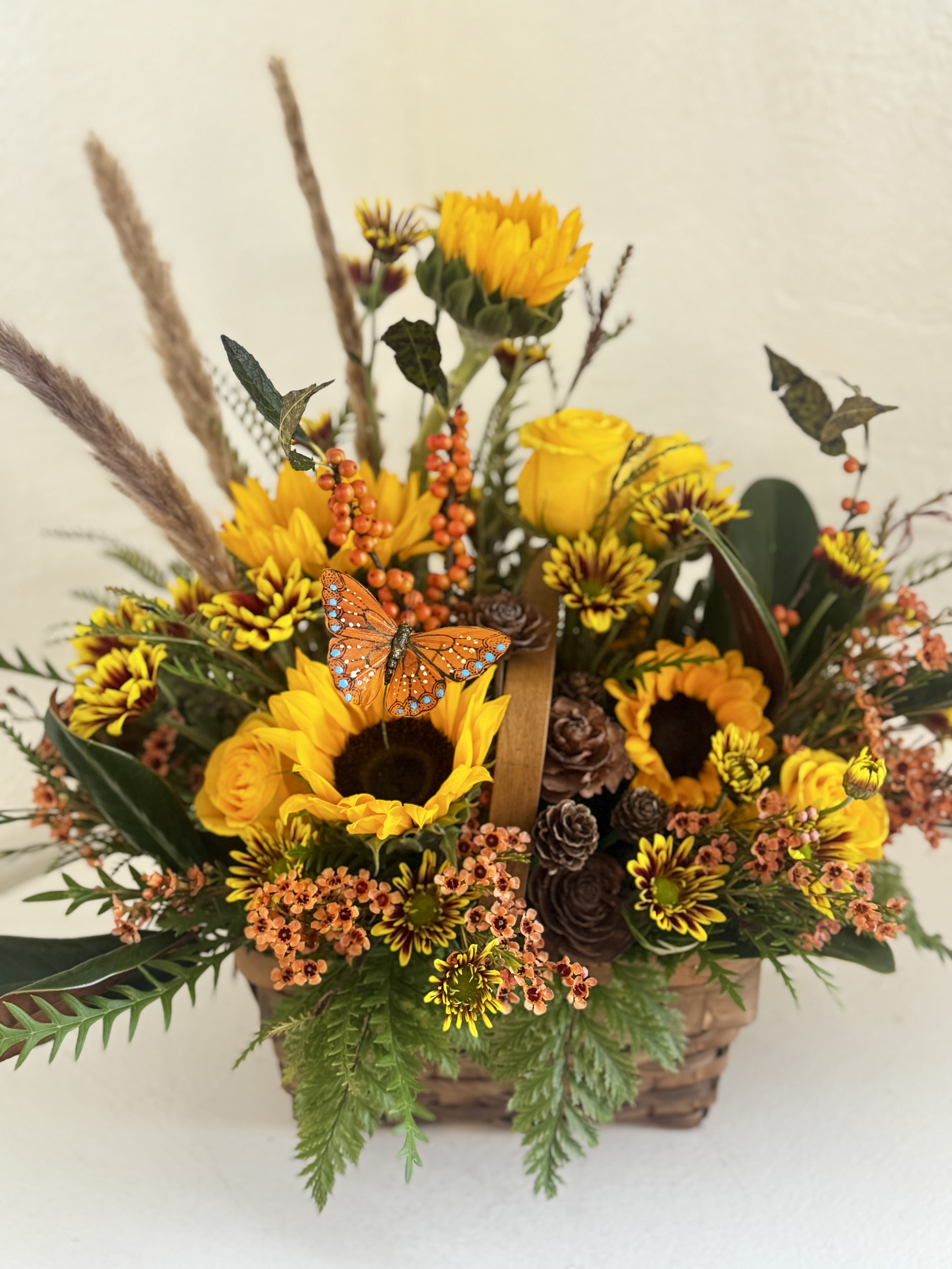Autumn flower basket with sunflowers, yellow roses, and an orange butterfly accent