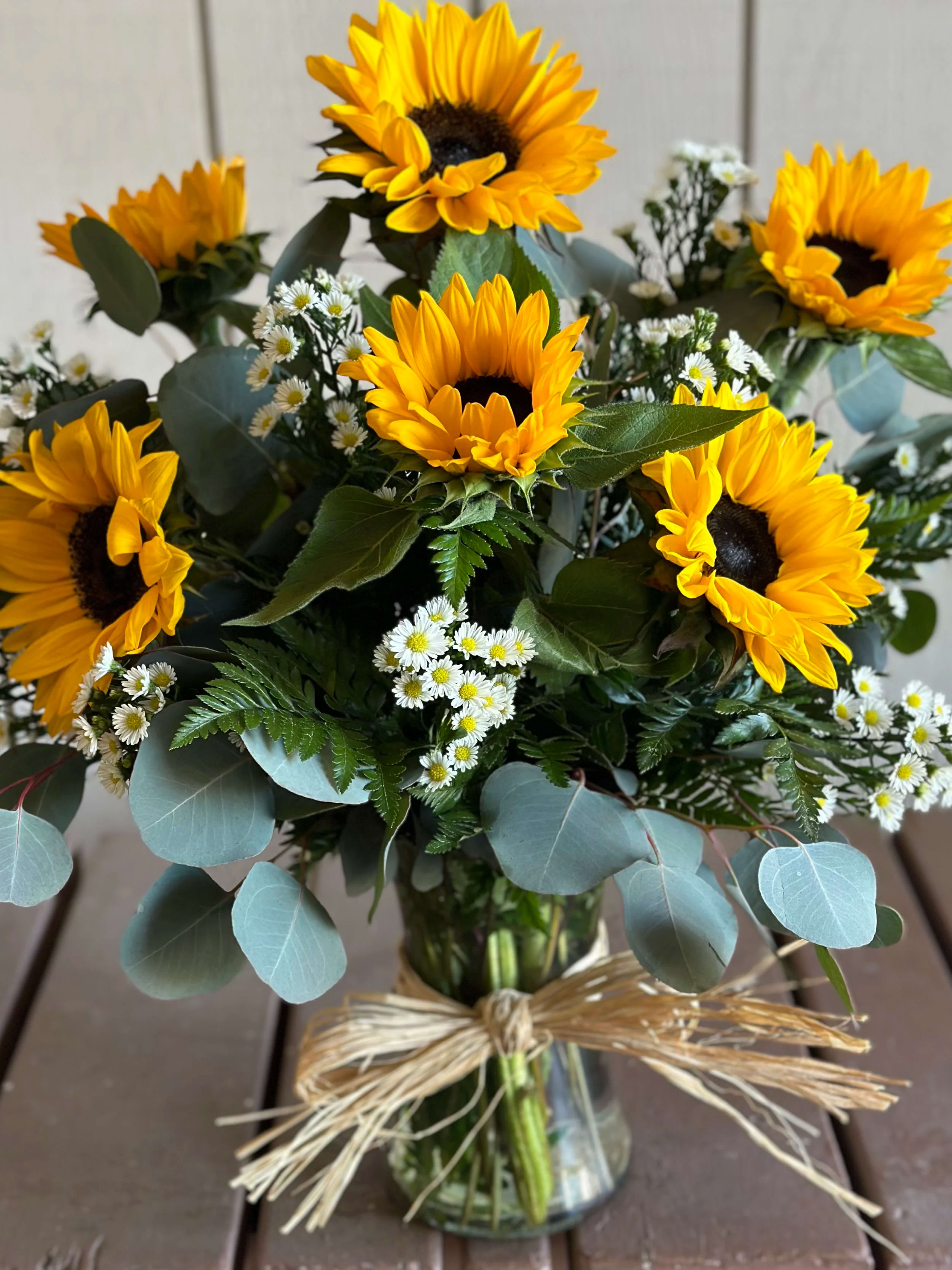 Bouquet of sunflowers and small white daisies in a glass vase