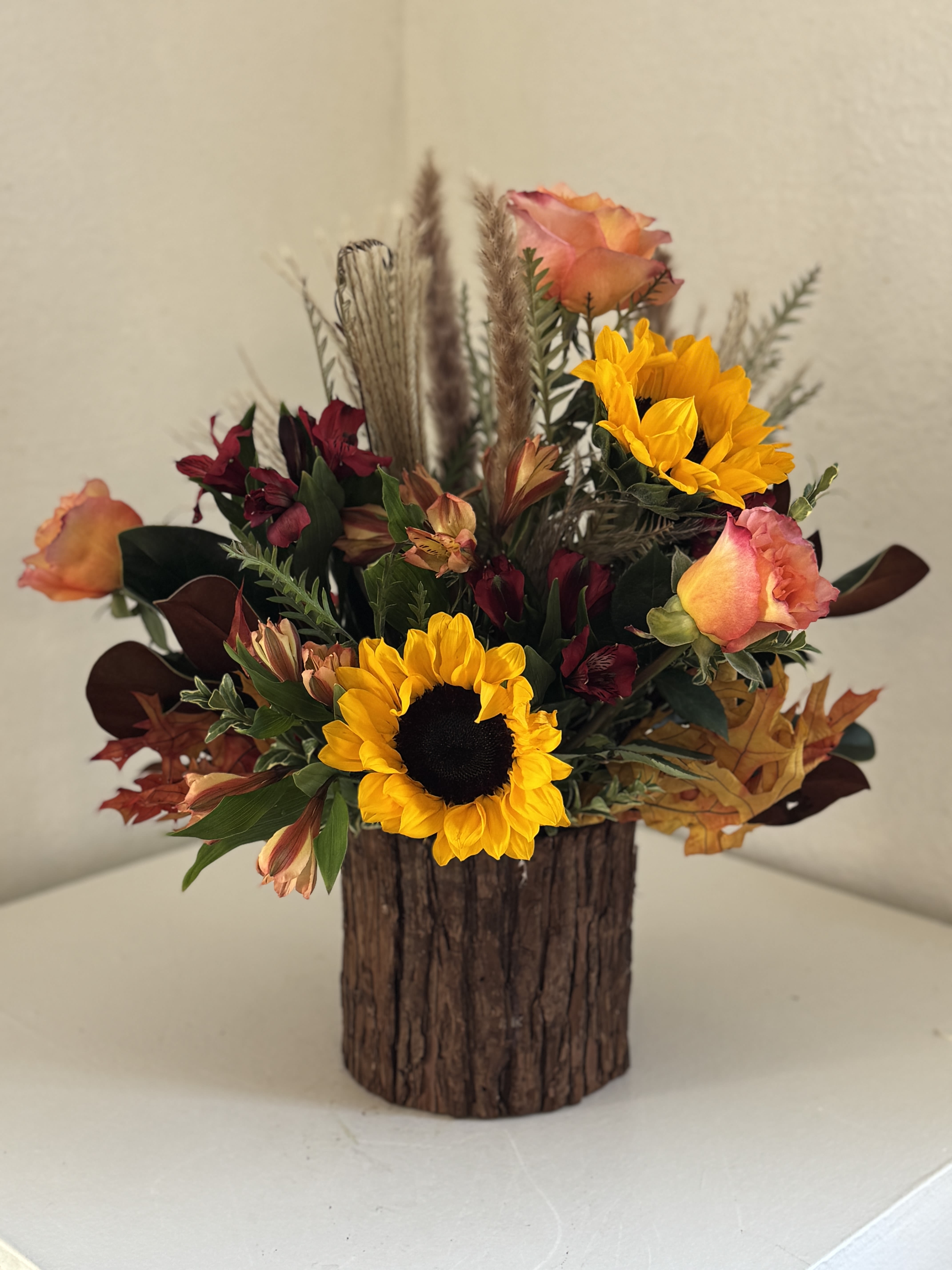 Sunflower and rose arrangement in a rustic wood container