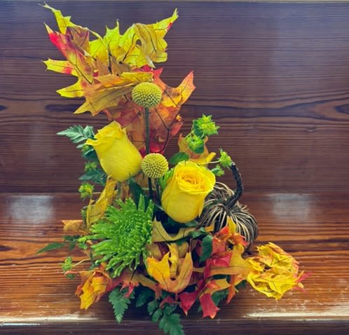 Yellow roses and green pom flowers with autumn leaves and a pumpkin accent