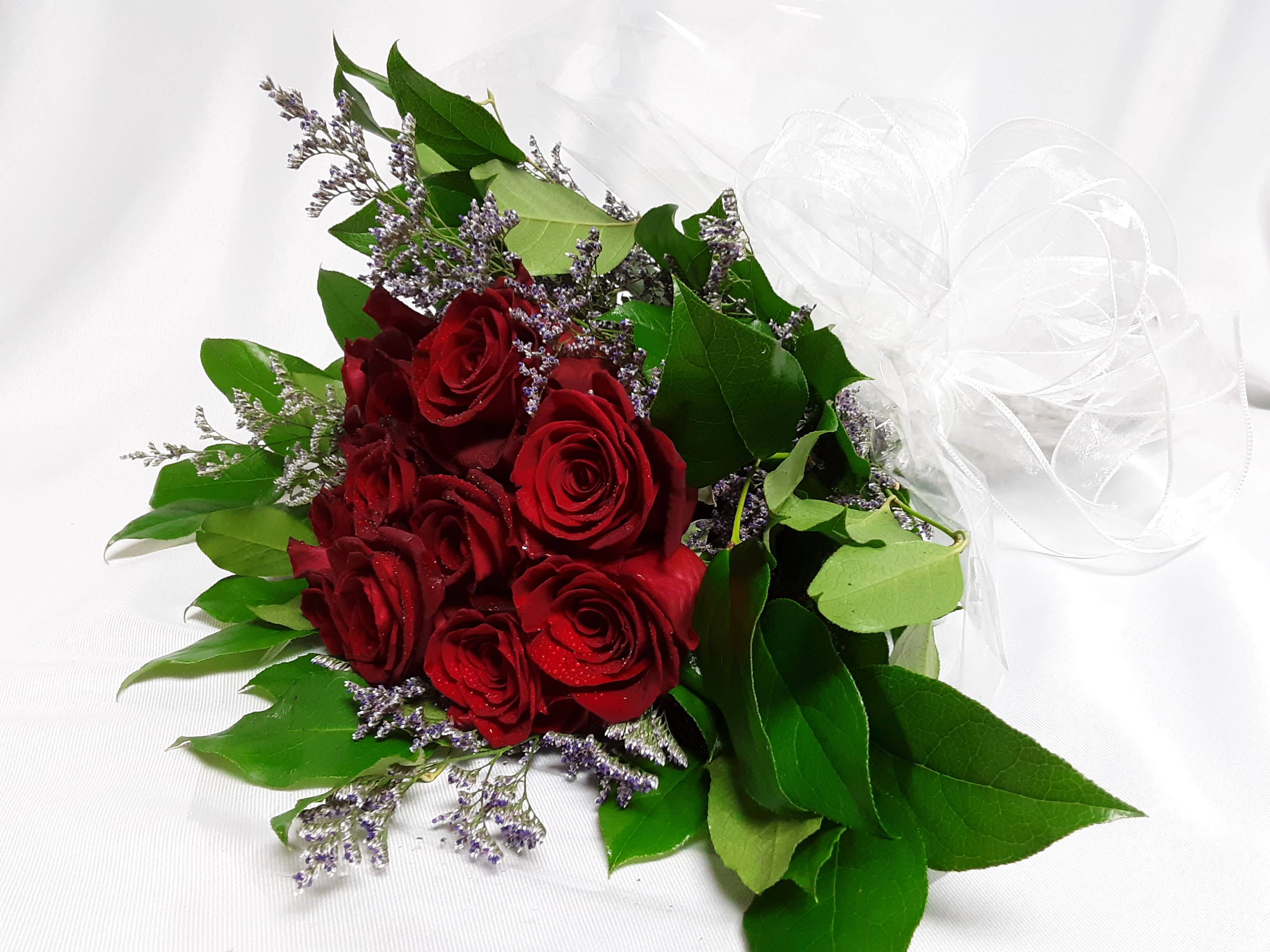 Bouquet of red roses with purple filler and a white ribbon bow