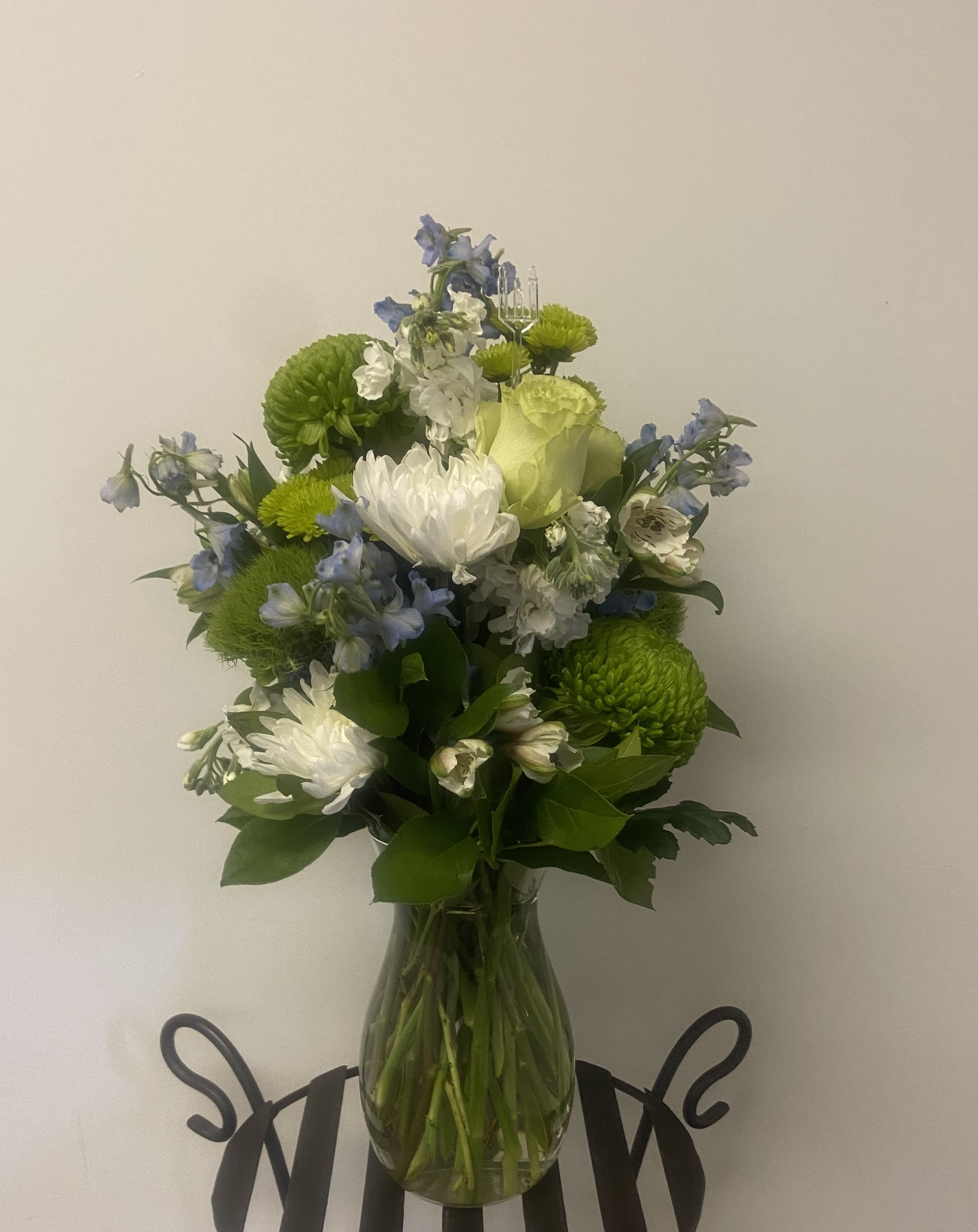 Bouquet of white, green, and blue flowers in a clear glass vase