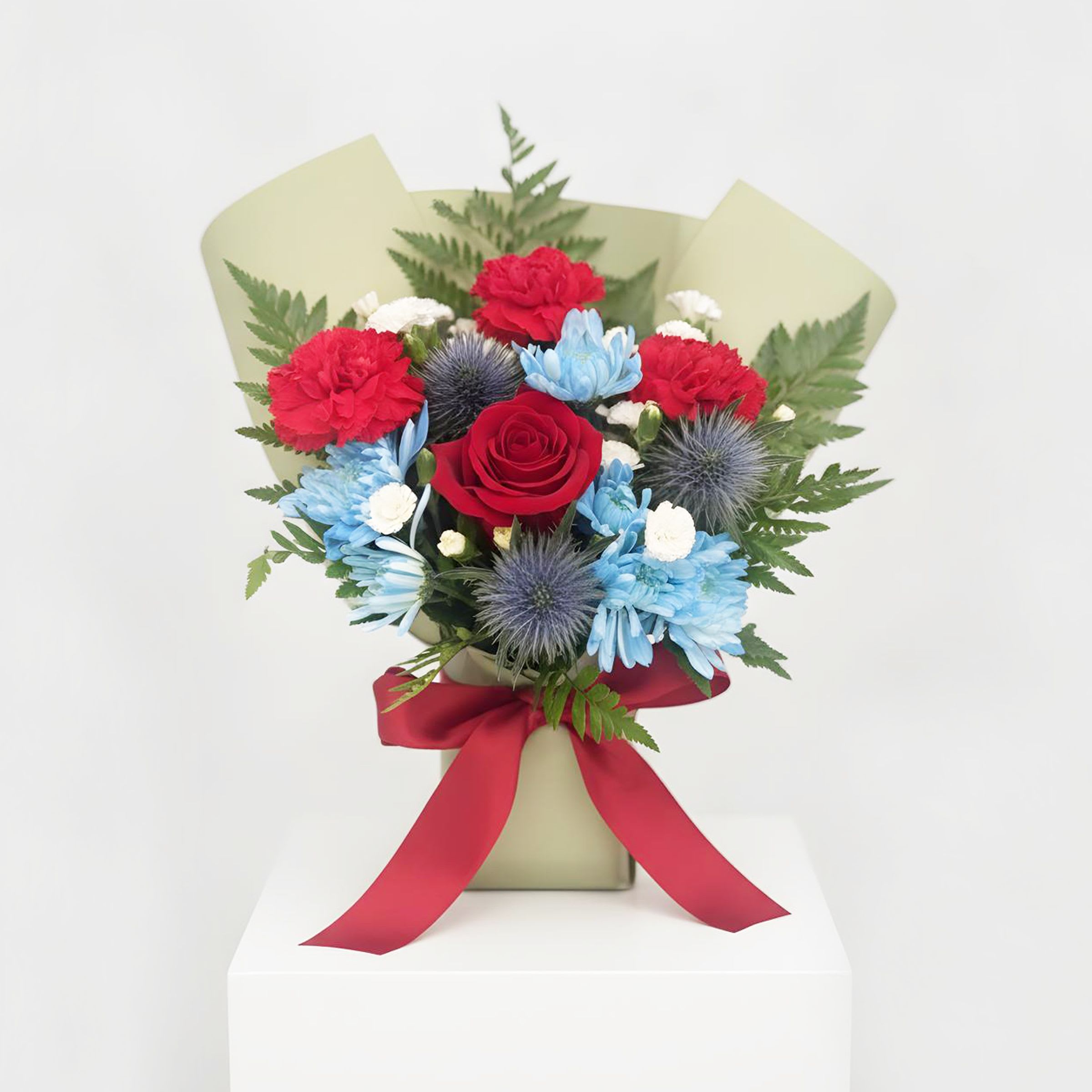 The #1 Hero - This striking bouquet features a powerful contrast of vibrant carnations reds and deep, royal blues, expertly wrapped in premium artisan paper. To make his day truly unforgettable. It is the ultimate mix of elegance, strength, and sweetness designed just for Dad.