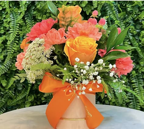 Bouquet of orange and pink flowers in a vase with an orange ribbon