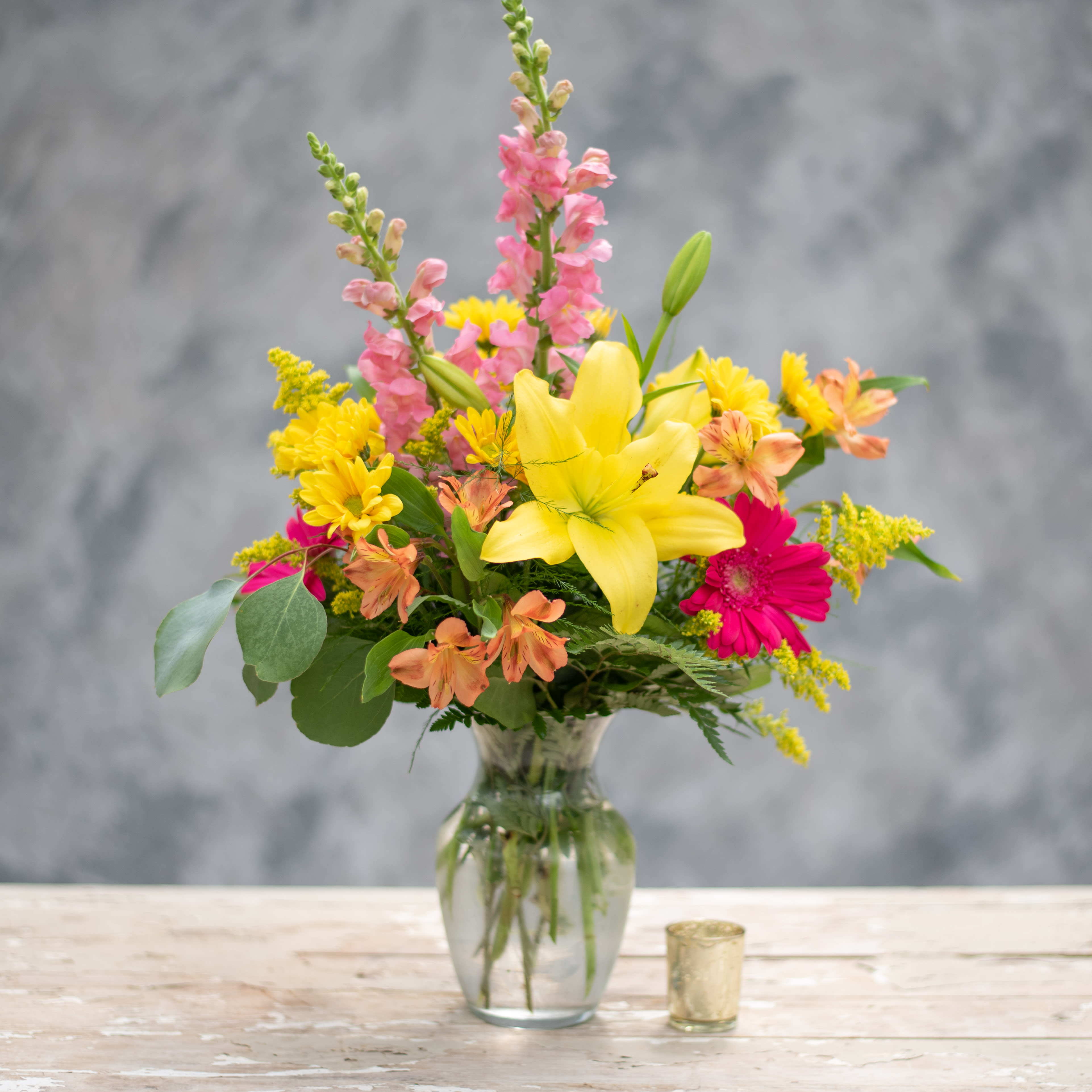 Garden Delight - A clear glass vase bursting with color - just like your Mom's Garden!  Including pink snap dragons, and gerbera daisies as well as yellow lilies and daisies along with premium greens and accent flowers.  
