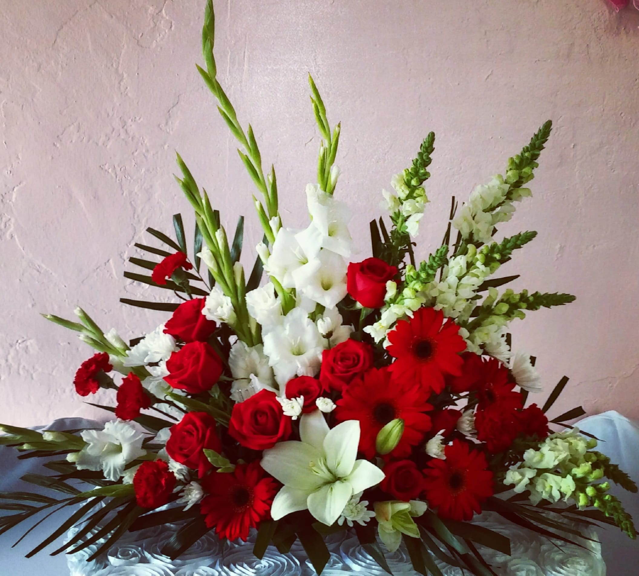 Red and white floral arrangement with roses, lilies, and gerbera daisies