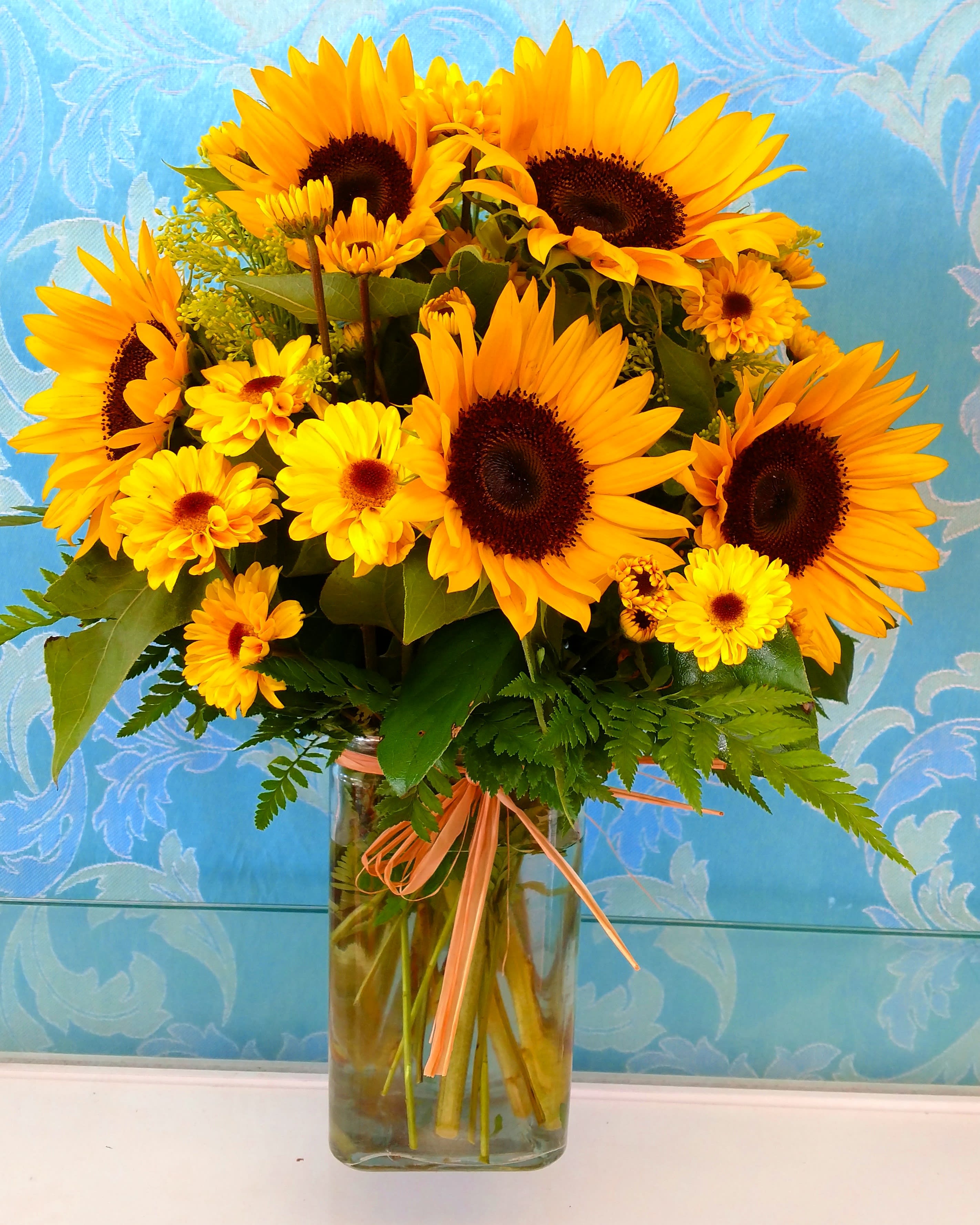 Sunflower and yellow daisy bouquet in a clear glass vase