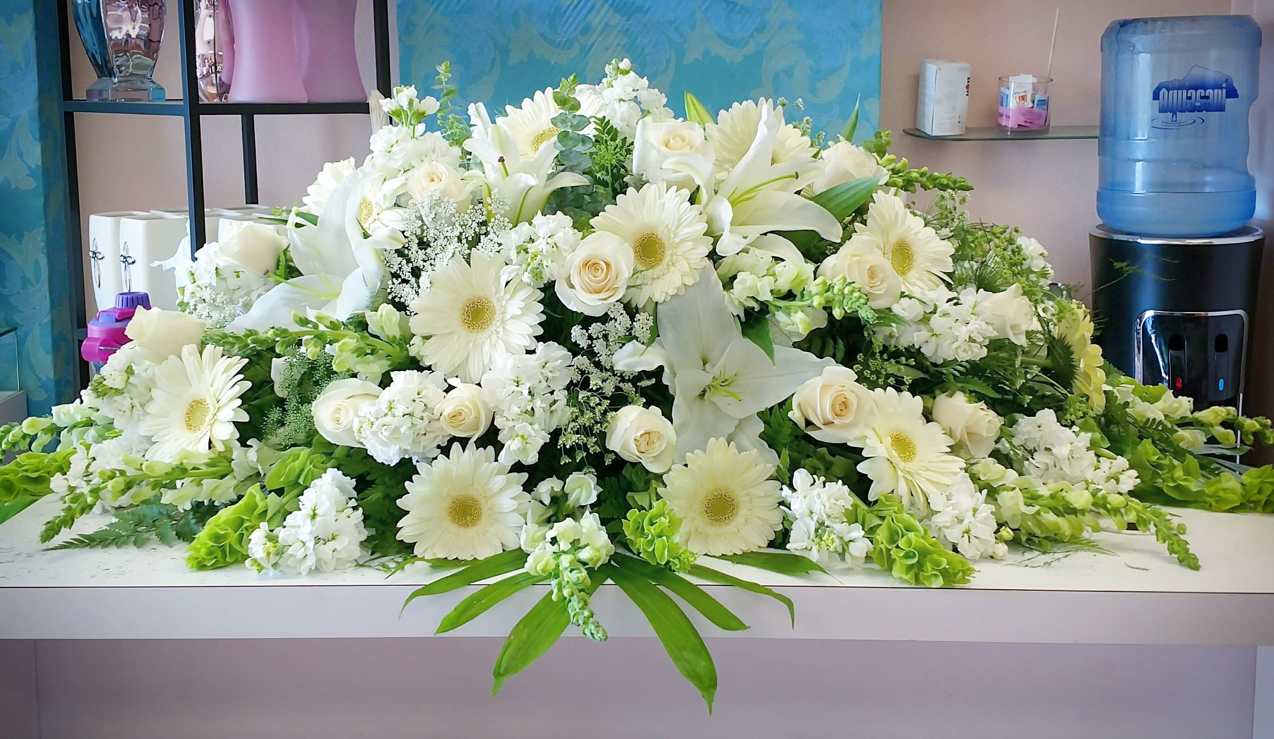 Large white floral arrangement with lilies, roses, and daisies on a table