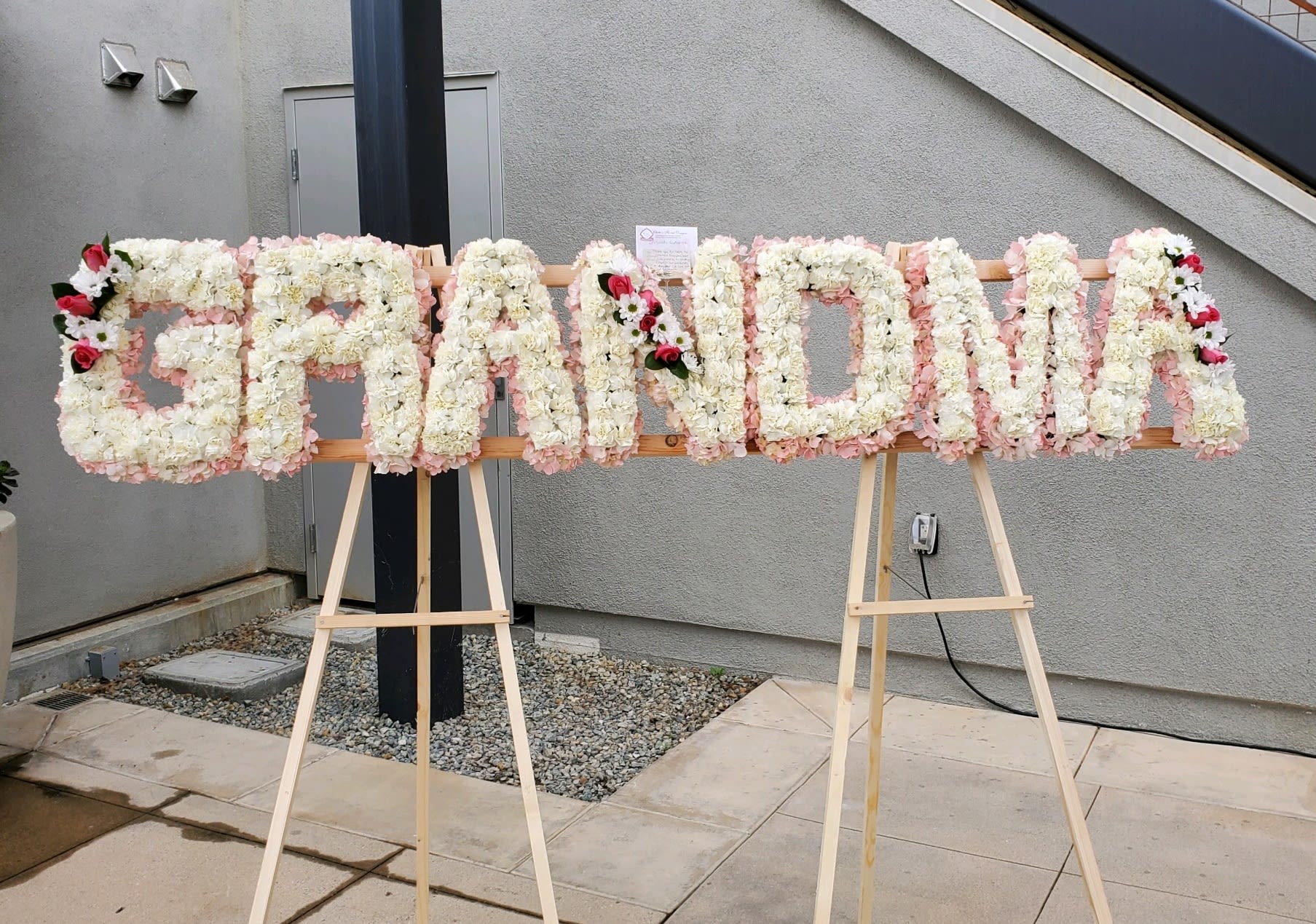 Floral sign spelling "GRANDMA" on easels with white and pink flowers