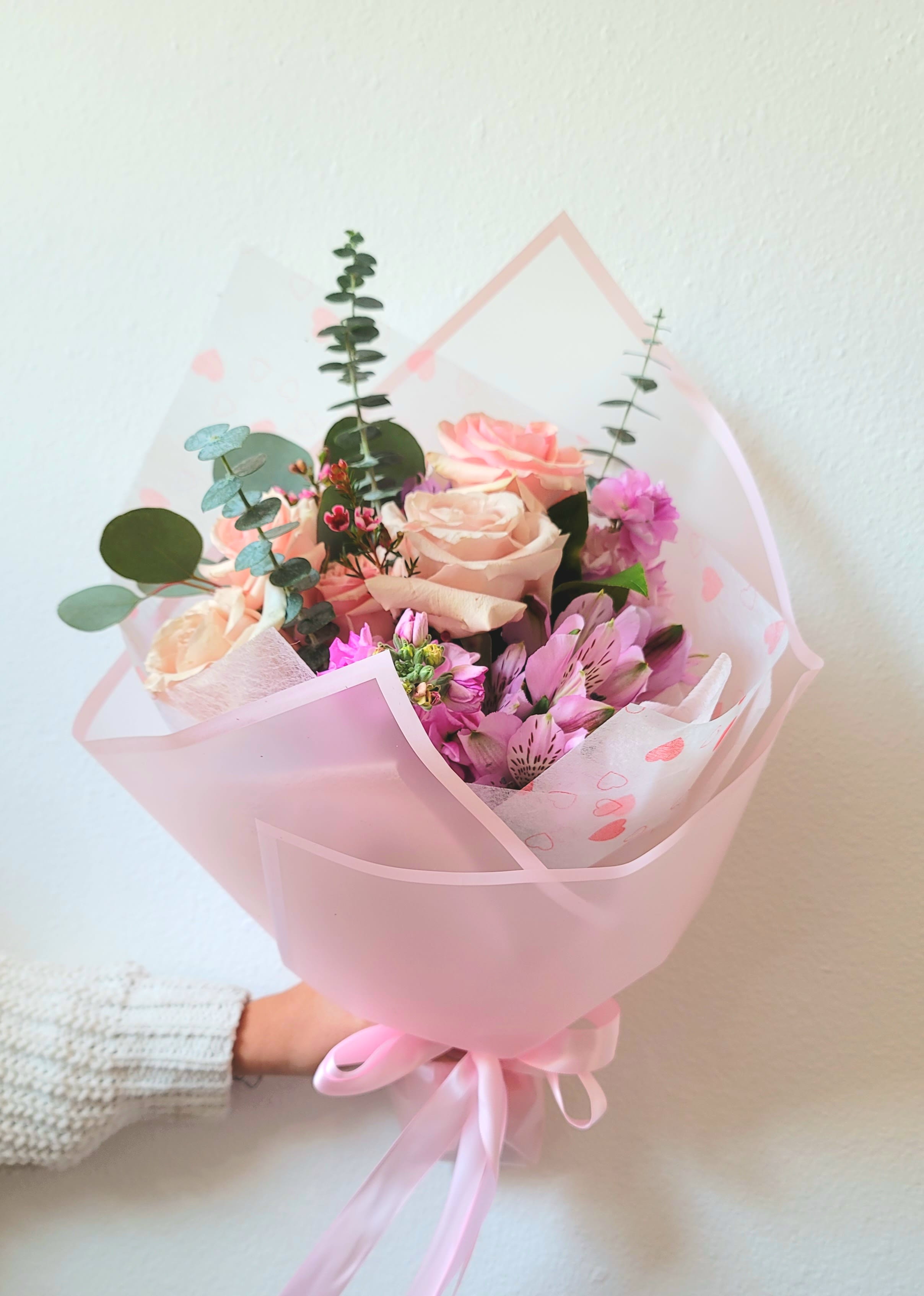 Pink and peach bouquet of roses and alstroemeria wrapped in pink paper