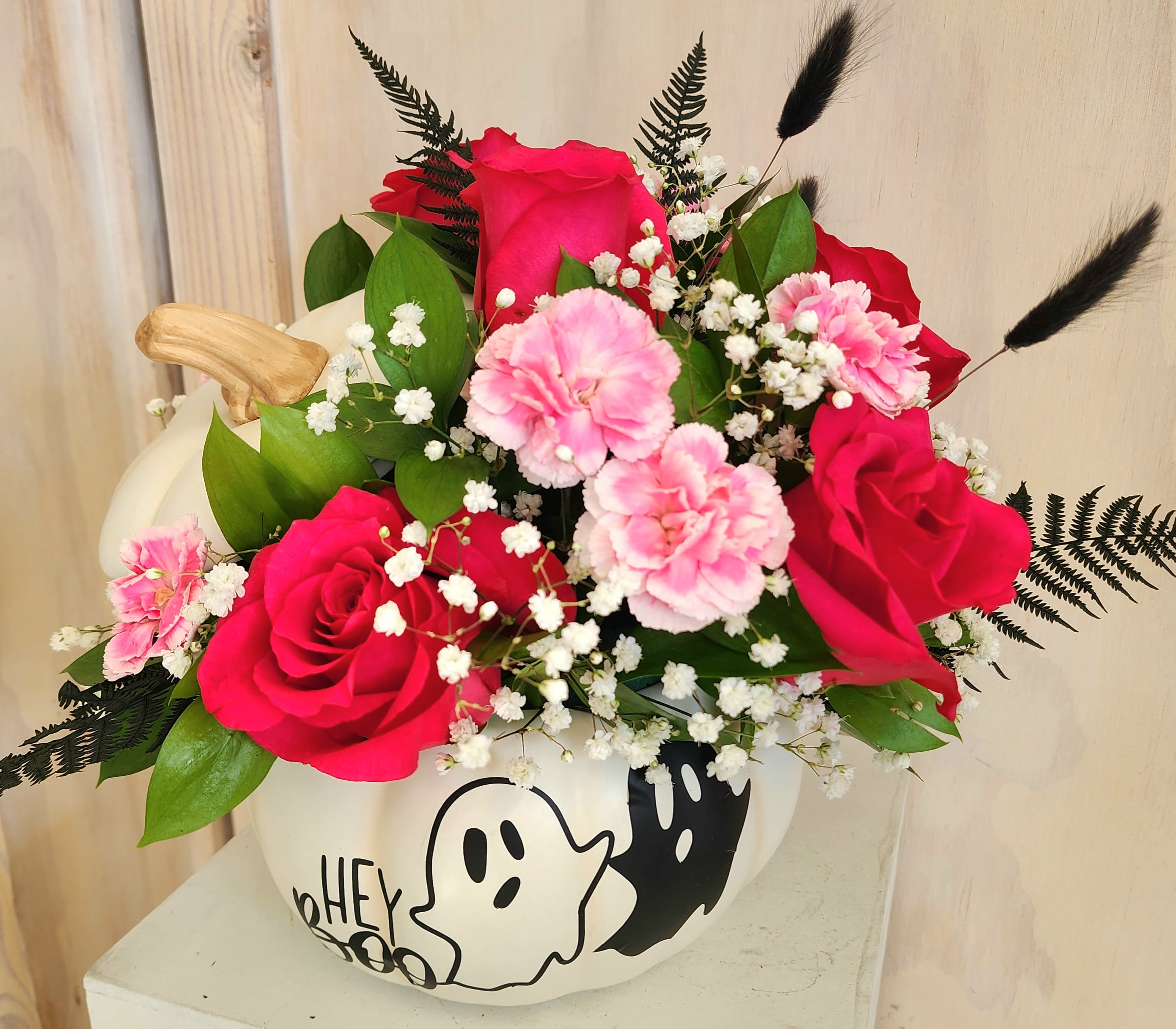 Pink and red rose bouquet with carnations in a white pumpkin vase